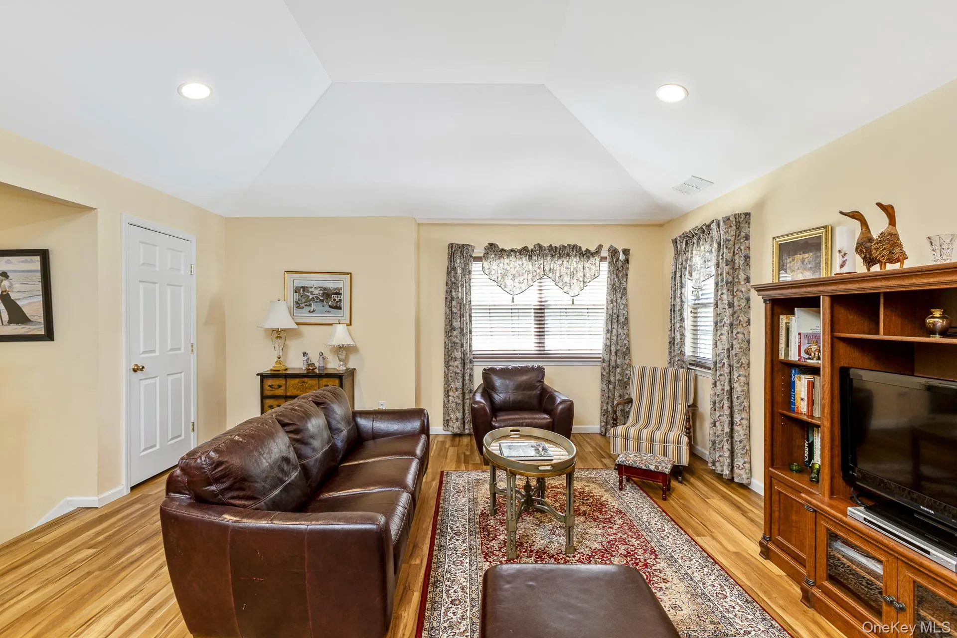 Living area featuring a vaulted ceiling with recessed lighting, wood-finish flooring Living area featuring a vaulted ceiling with recessed lighting, wood-finish flooring