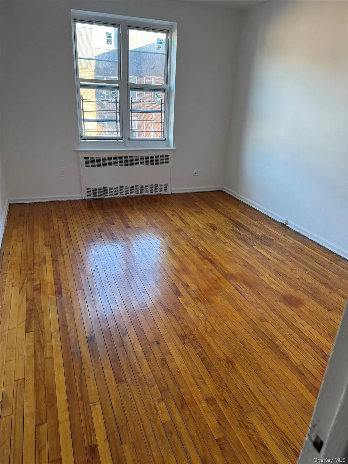 Unfurnished room with radiator and light wood finished floors Unfurnished room with radiator and light wood finished floors
