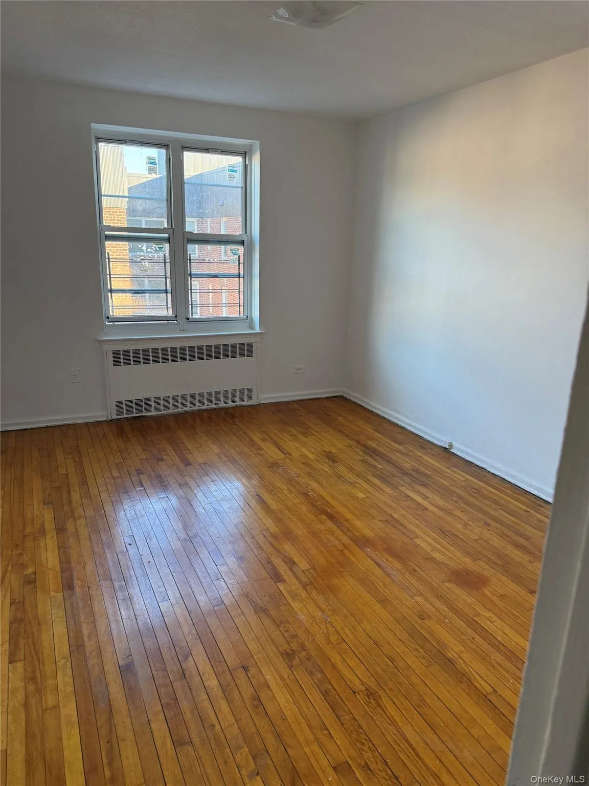 Unfurnished room with radiator and hardwood / wood-style flooring Unfurnished room with radiator and hardwood / wood-style flooring