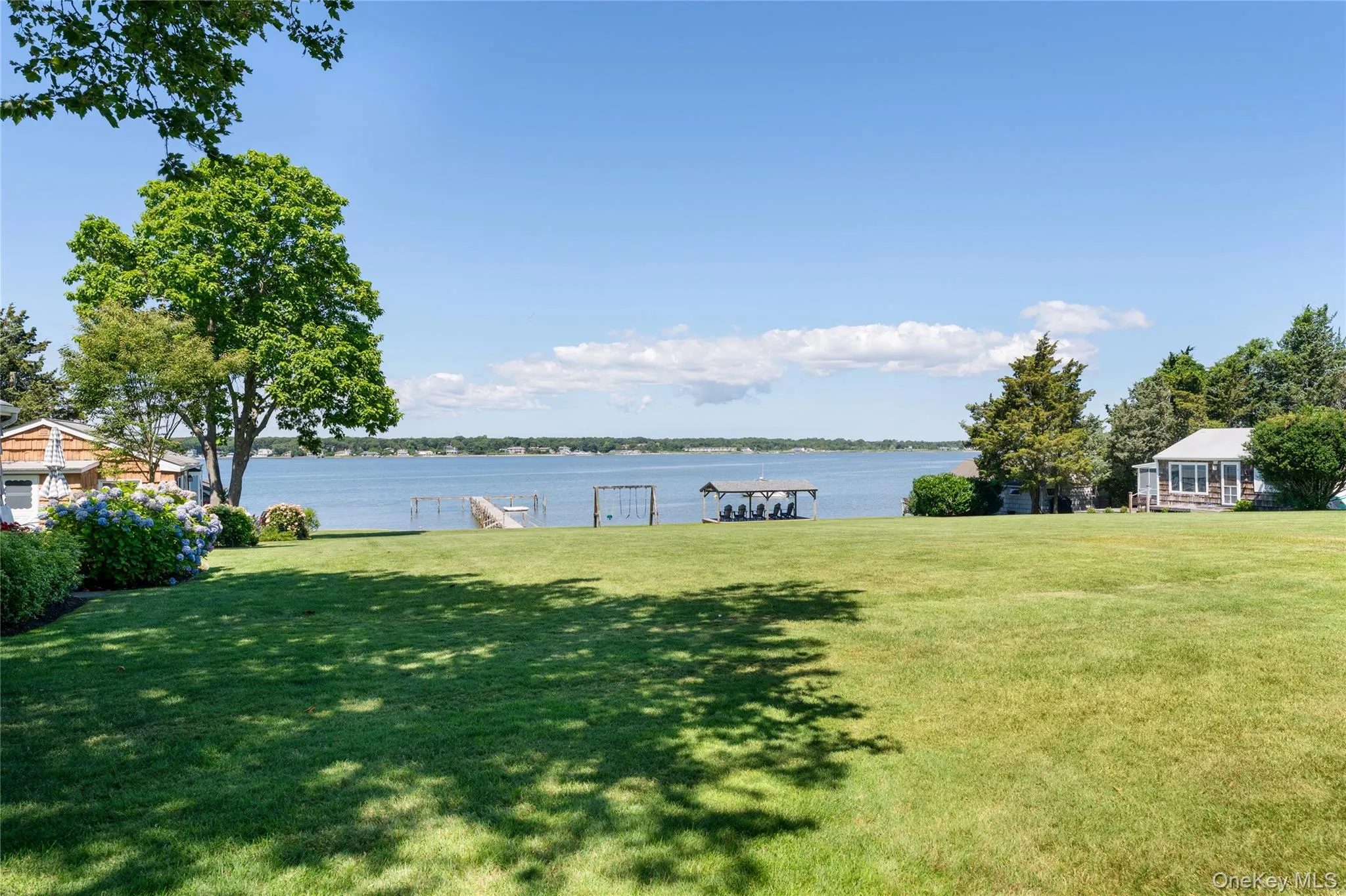 View of grassy yard featuring a water view and a boat dock View of grassy yard featuring a water view and a boat dock