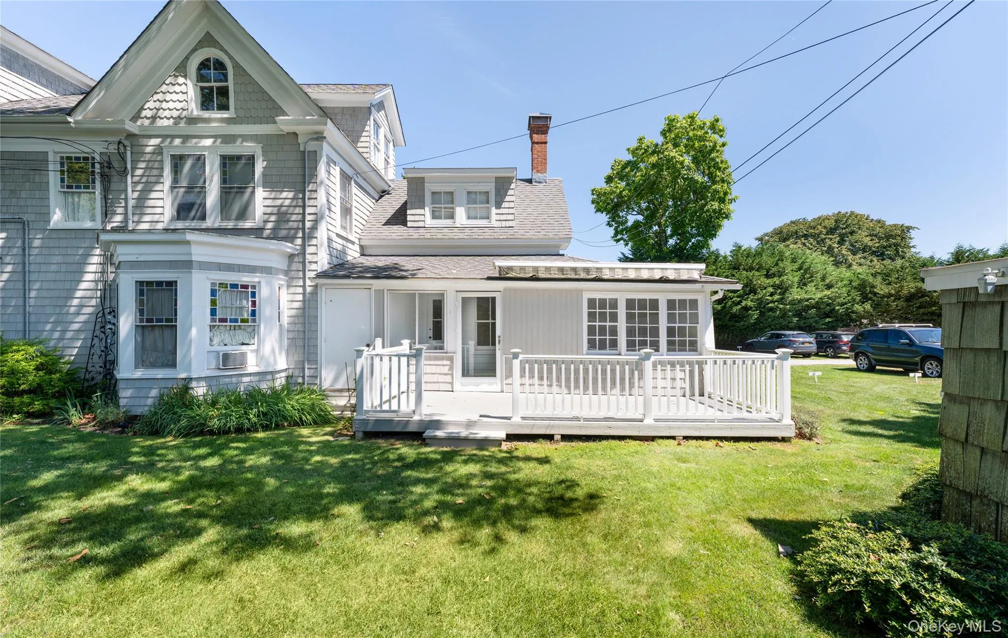 Rear view of house with a chimney, a shingled roof, a lawn, and a wooden deck Rear view of house with a chimney, a shingled roof, a lawn, and a wooden deck