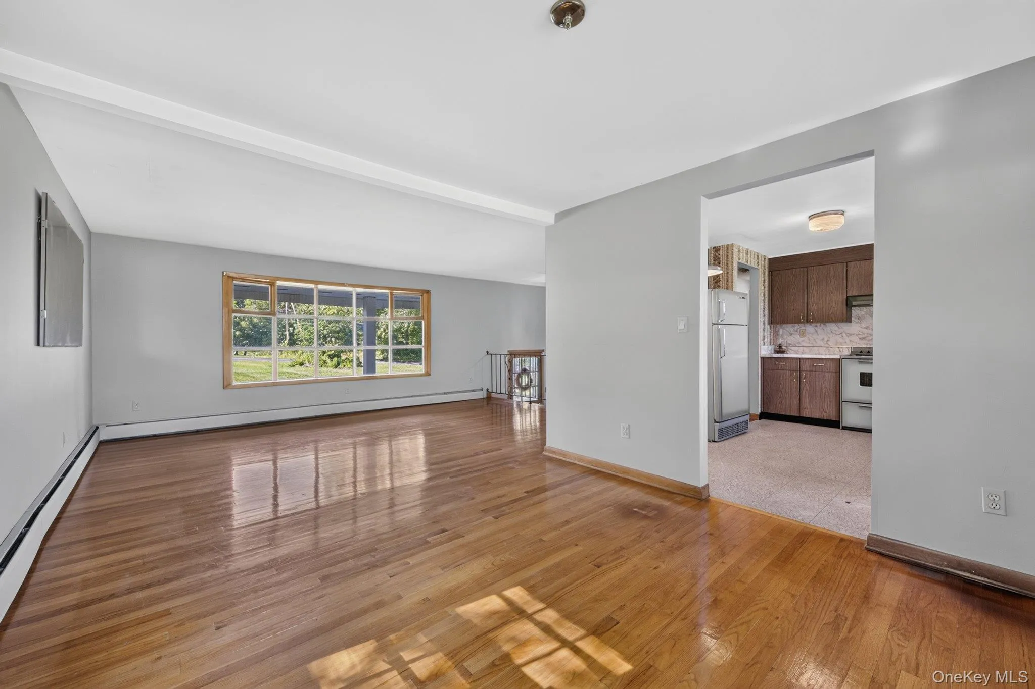 Expansive living area featuring wood-finish flooring and a large picture window Expansive living area featuring wood-finish flooring and a large picture window