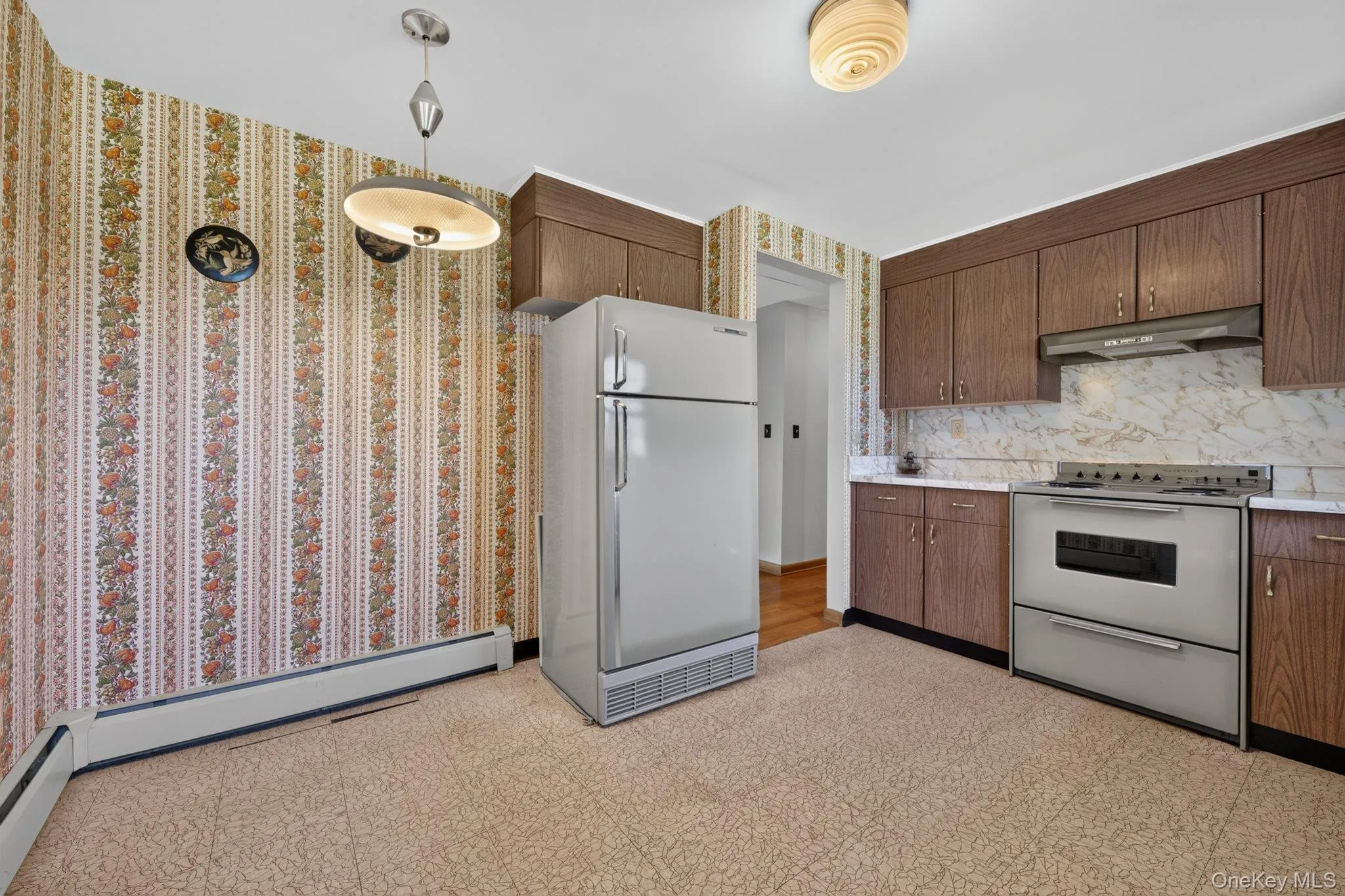 Kitchen featuring wood-finish cabinetry, light-toned countertops, a built-in range with an overhead exhaust, and a patterned backsplash Kitchen featuring wood-finish cabinetry, light-toned countertops, a built-in range with an overhead exhaust, and a patterned backsplash