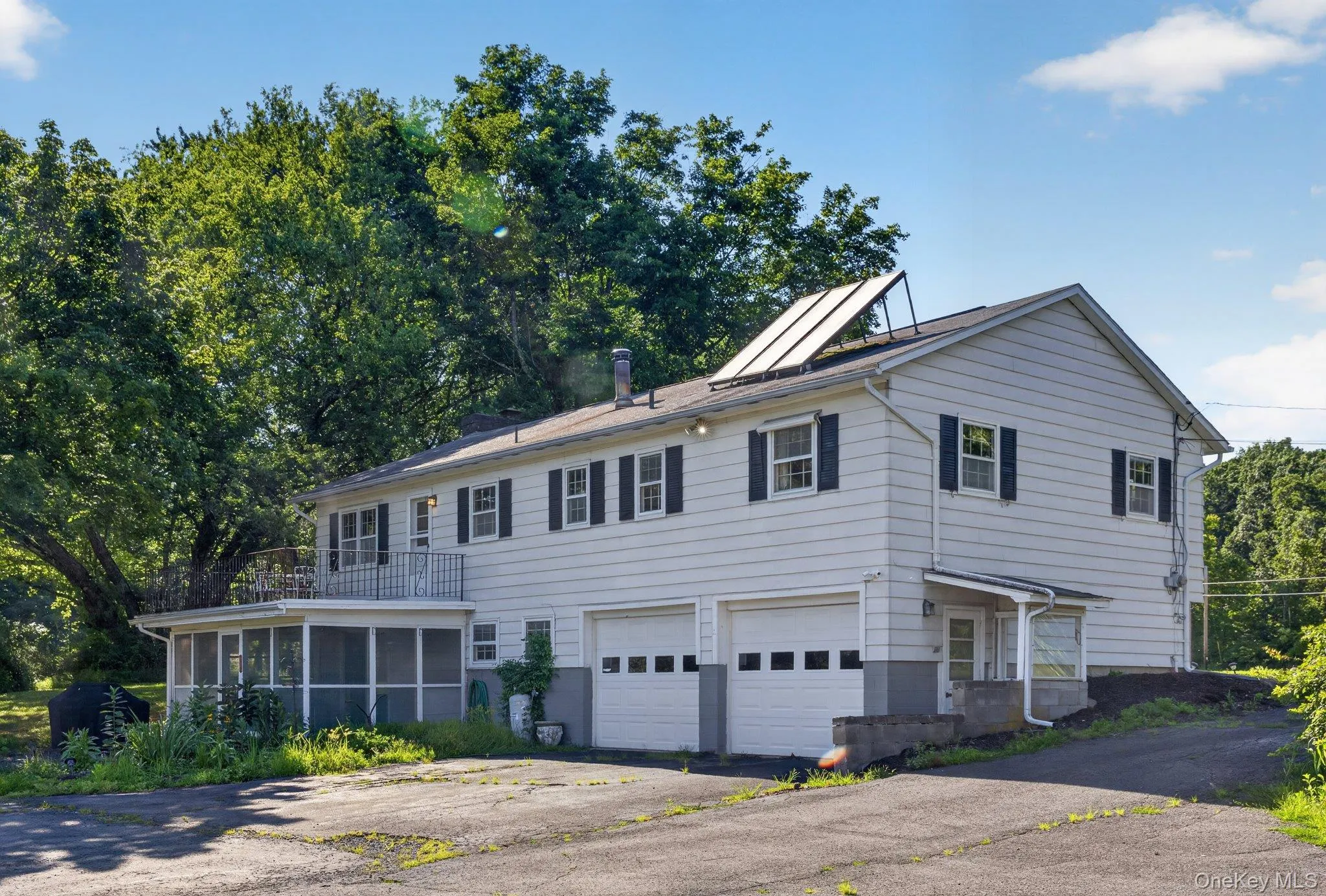 White siding exterior with black shutters, featuring a two-car garage with panel doors White siding exterior with black shutters, featuring a two-car garage with panel doors