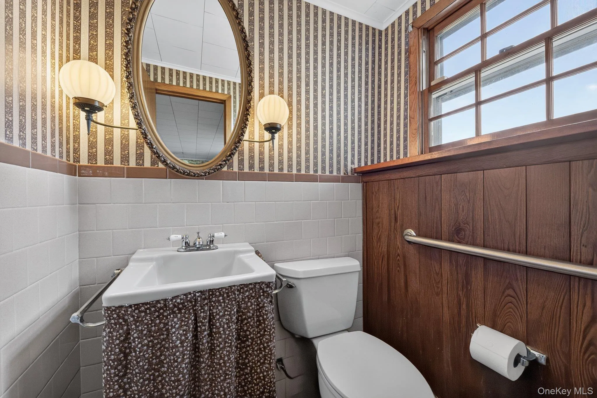 Bathroom with wood-finish paneling, white ceramic tile, and patterned wallpaper Bathroom with wood-finish paneling, white ceramic tile, and patterned wallpaper