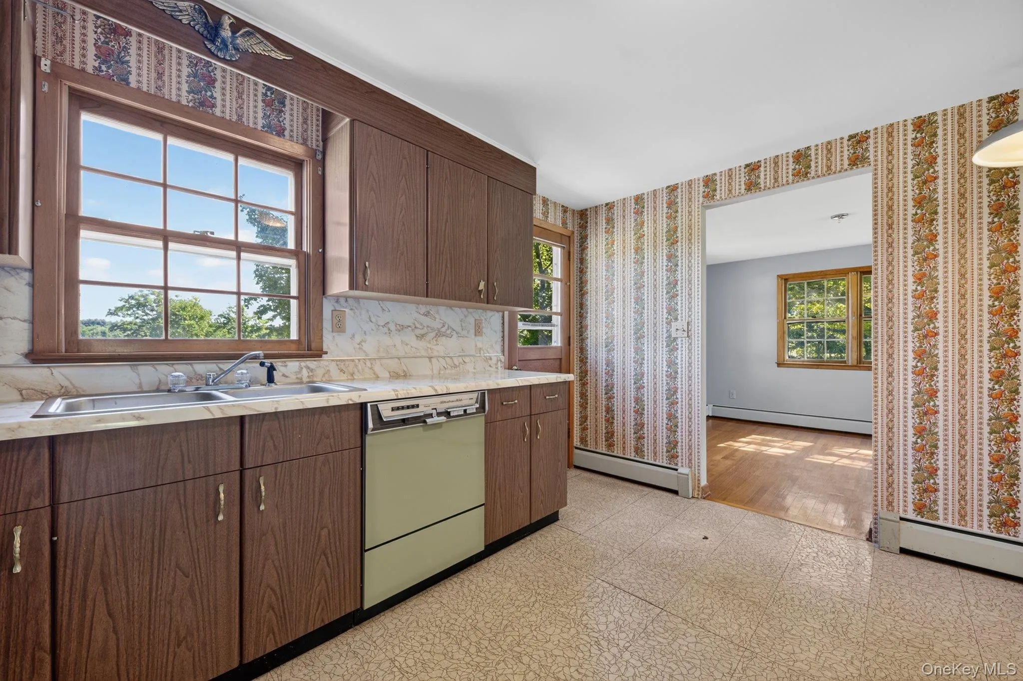 Kitchen featuring wood-finish cabinetry, a double basin stainless steel sink, and a built-in dishwasher Kitchen featuring wood-finish cabinetry, a double basin stainless steel sink, and a built-in dishwasher