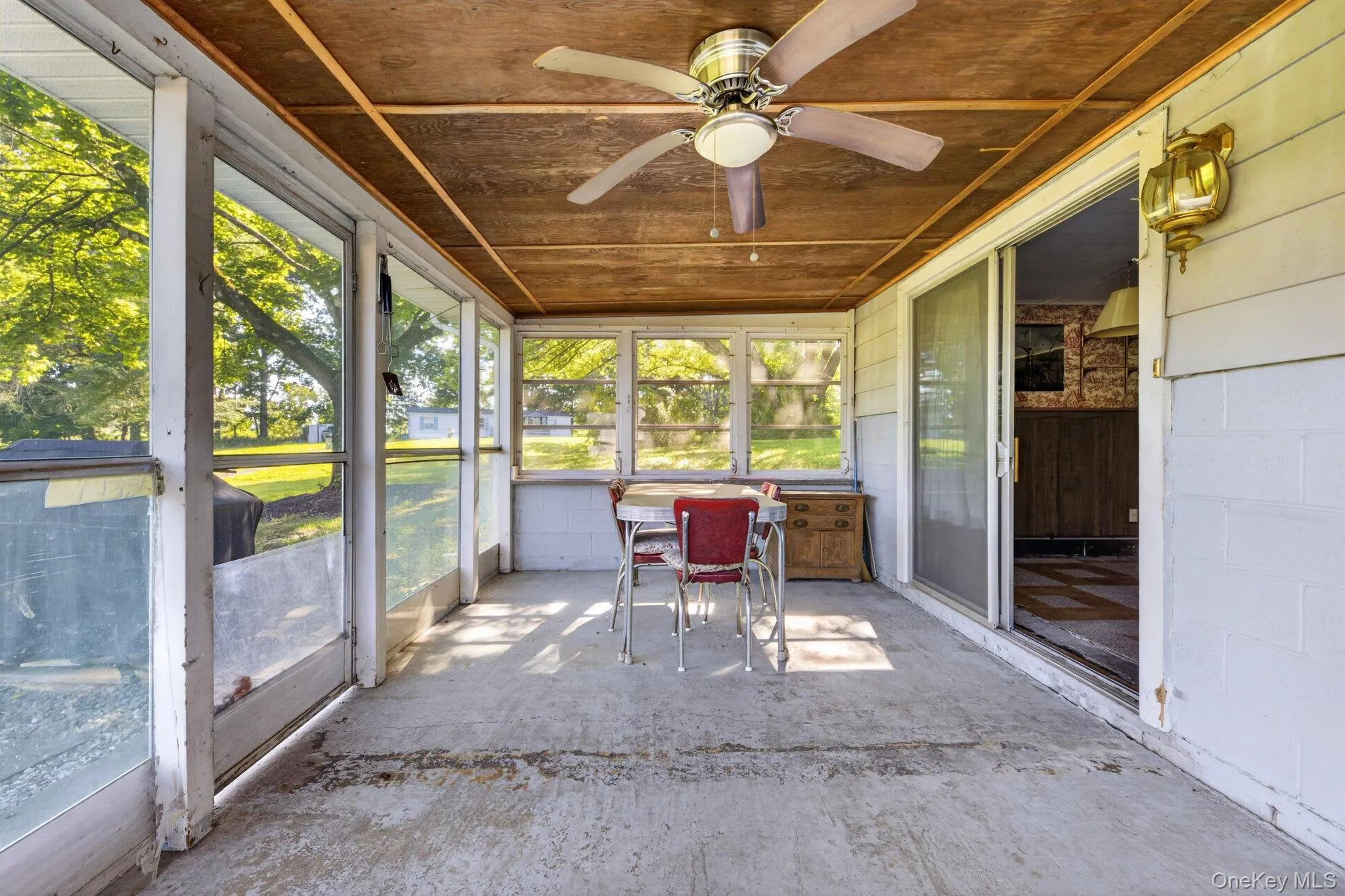 Screened porch featuring a concrete floor, wood-finish ceiling, and a ceiling fan Screened porch featuring a concrete floor, wood-finish ceiling, and a ceiling fan