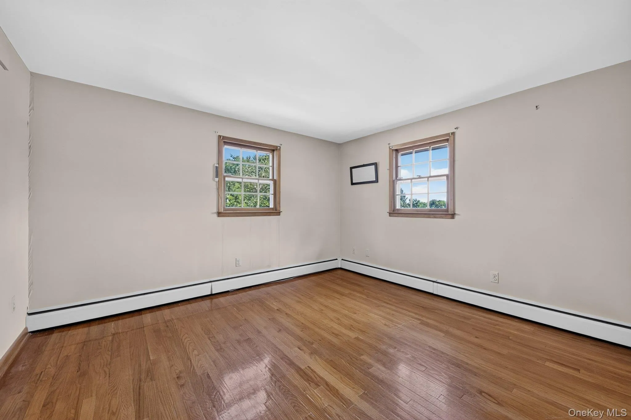 Hardwood flooring, neutral wall paint, and two windows with wood trim Hardwood flooring, neutral wall paint, and two windows with wood trim