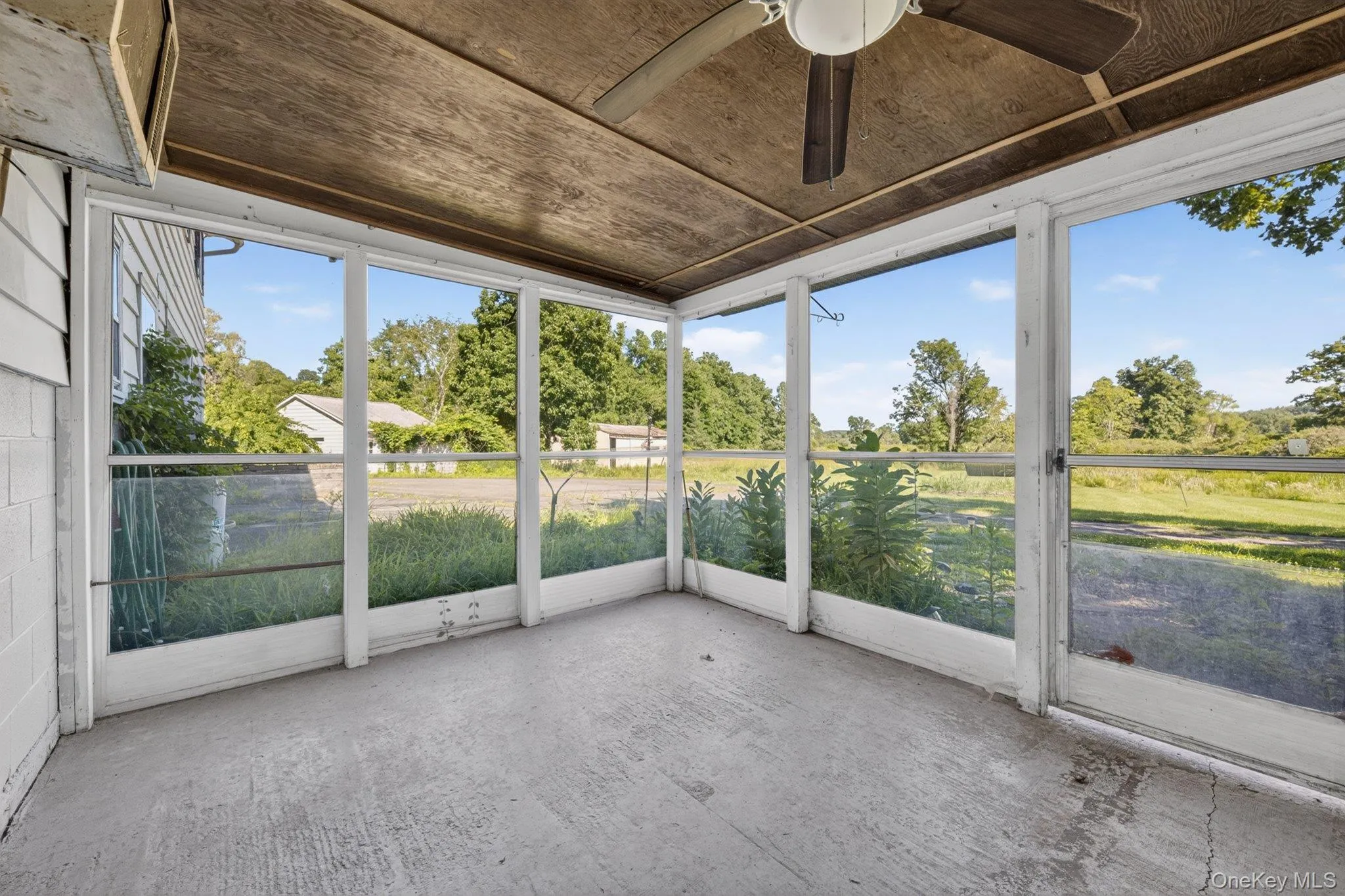 Screened porch featuring a ceiling fan, concrete flooring, and multiple window panels Screened porch featuring a ceiling fan, concrete flooring, and multiple window panels
