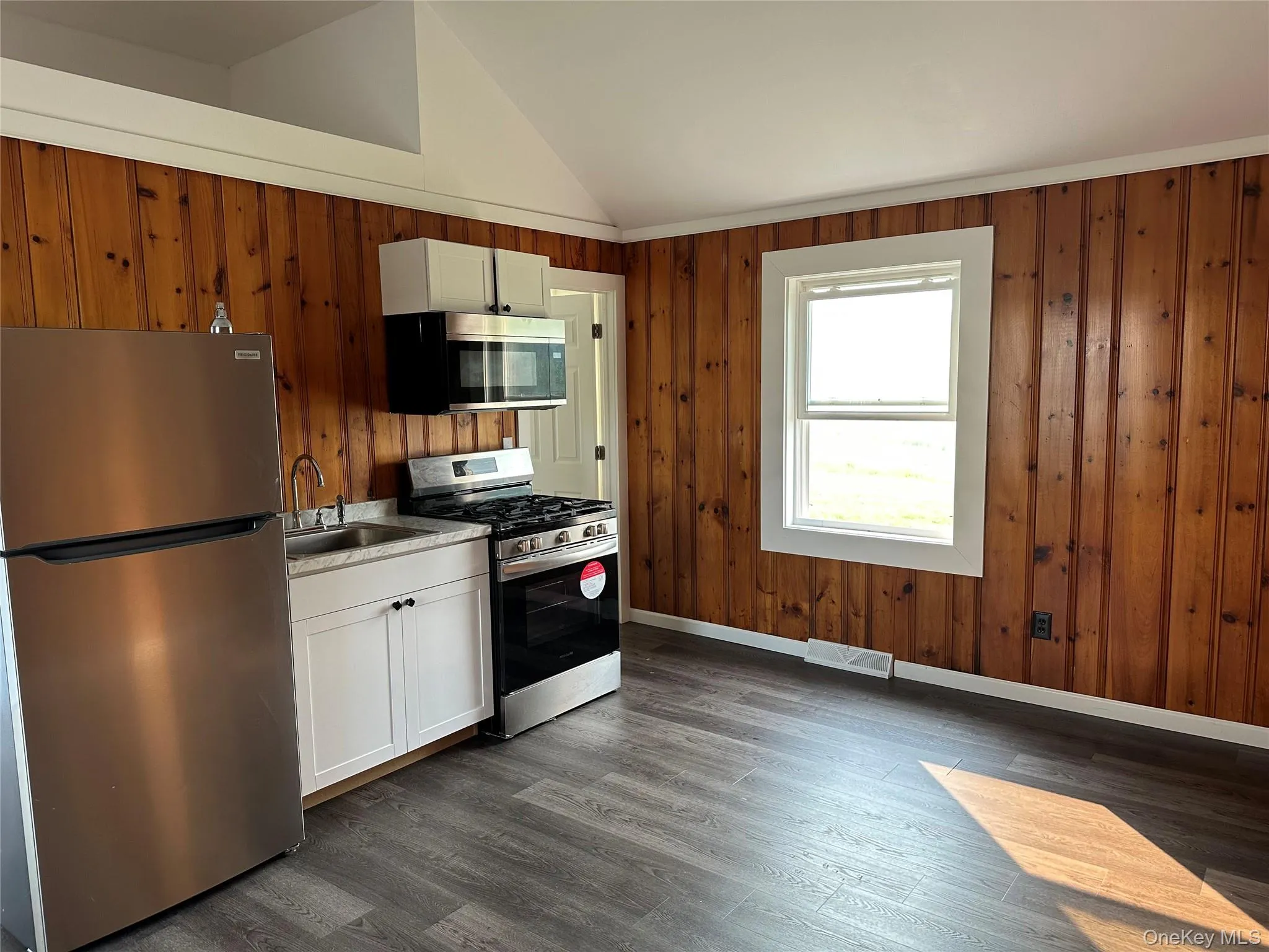 Kitchen area featuring wood paneling and a large window Kitchen area featuring wood paneling and a large window