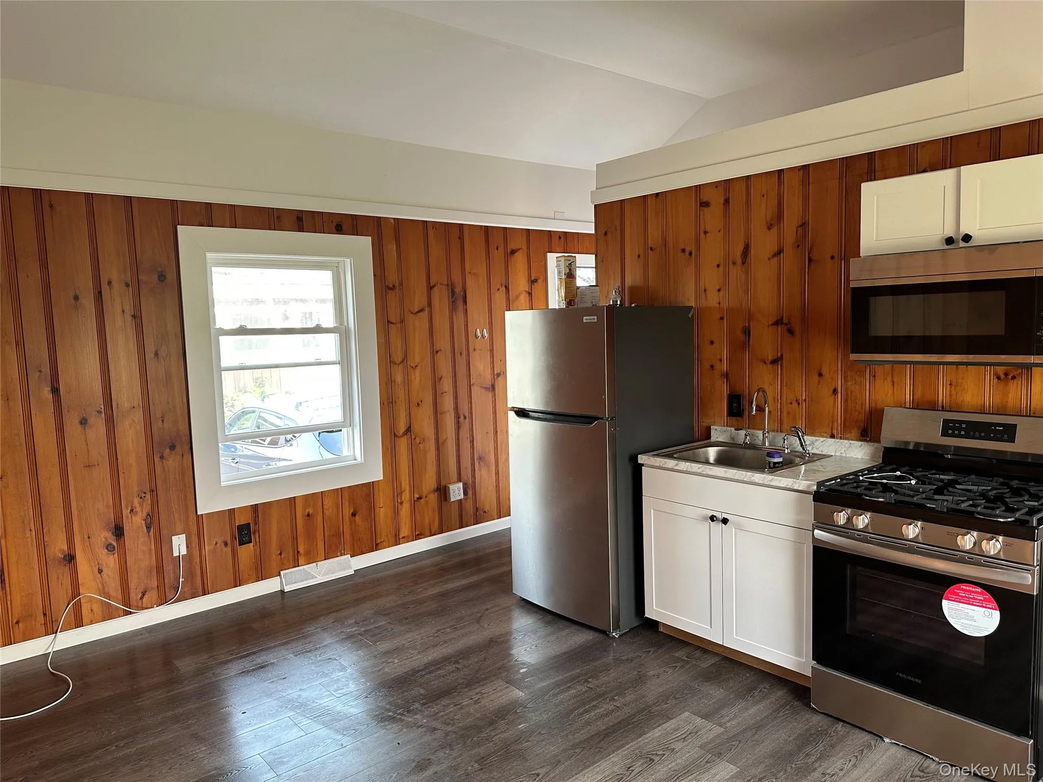 Kitchenette featuring stainless steel appliances, white cabinetry, and wood-finish flooring Kitchenette featuring stainless steel appliances, white cabinetry, and wood-finish flooring