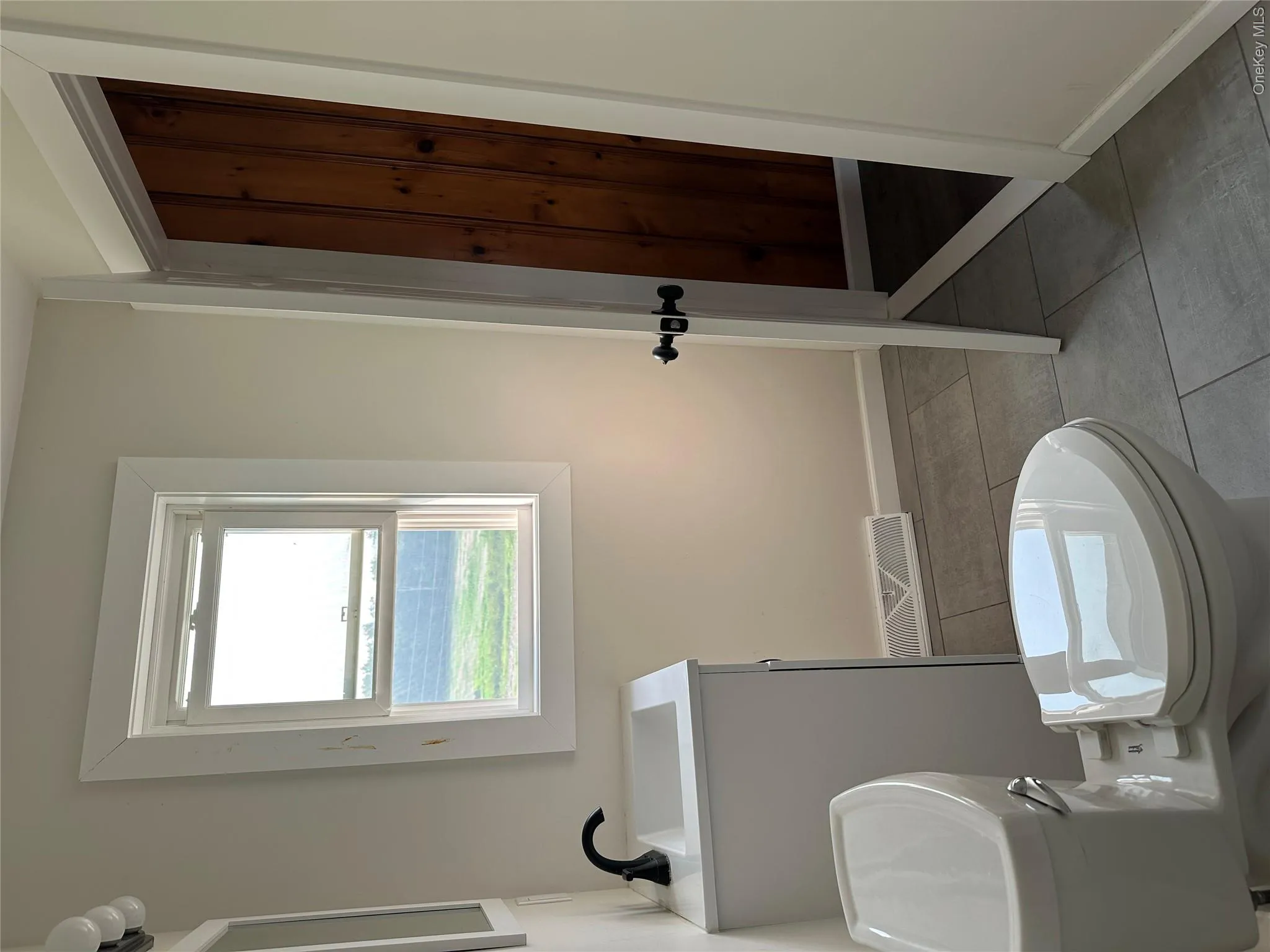Bathroom featuring a white vanity with integrated sink and matte black faucet, a dual-flush toilet, and gray tile flooring Bathroom featuring a white vanity with integrated sink and matte black faucet, a dual-flush toilet, and gray tile flooring