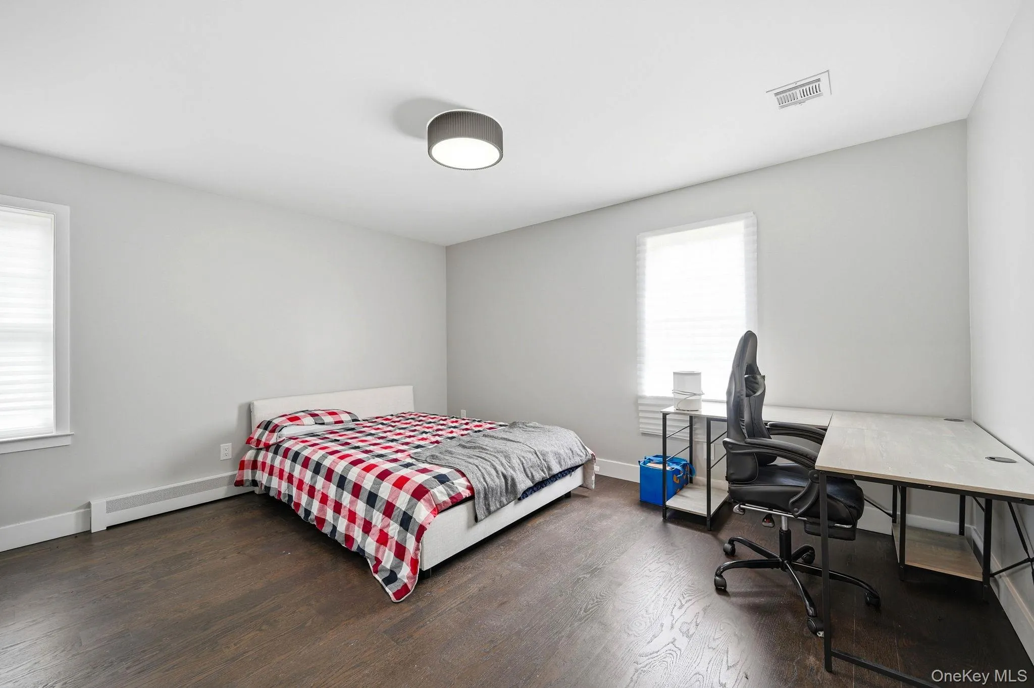 Spacious room featuring wood-finish flooring, light grey painted walls, and white baseboards Spacious room featuring wood-finish flooring, light grey painted walls, and white baseboards