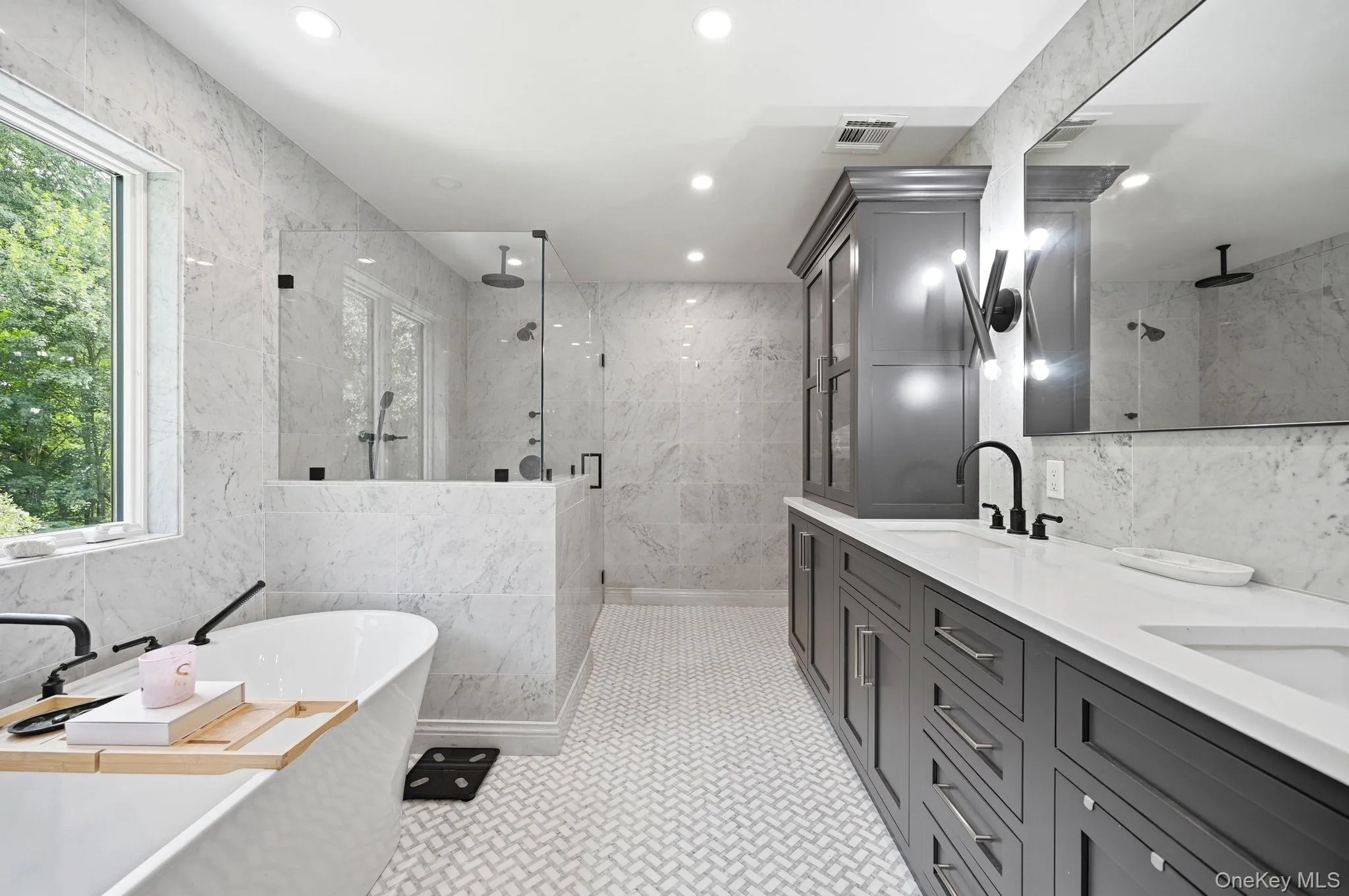 Spacious bathroom featuring a Fleurco Opus Collection freestanding soaking tub, a large glass-enclosed shower, dual vanity with undermount sinks, custom cabinetry, premium Kohler Bidet toilet and heated marble flooring Spacious bathroom featuring a Fleurco Opus Collection freestanding soaking tub, a large glass-enclosed shower, dual vanity with undermount sinks, custom cabinetry, premium Kohler Bidet toilet and heated marble flooring