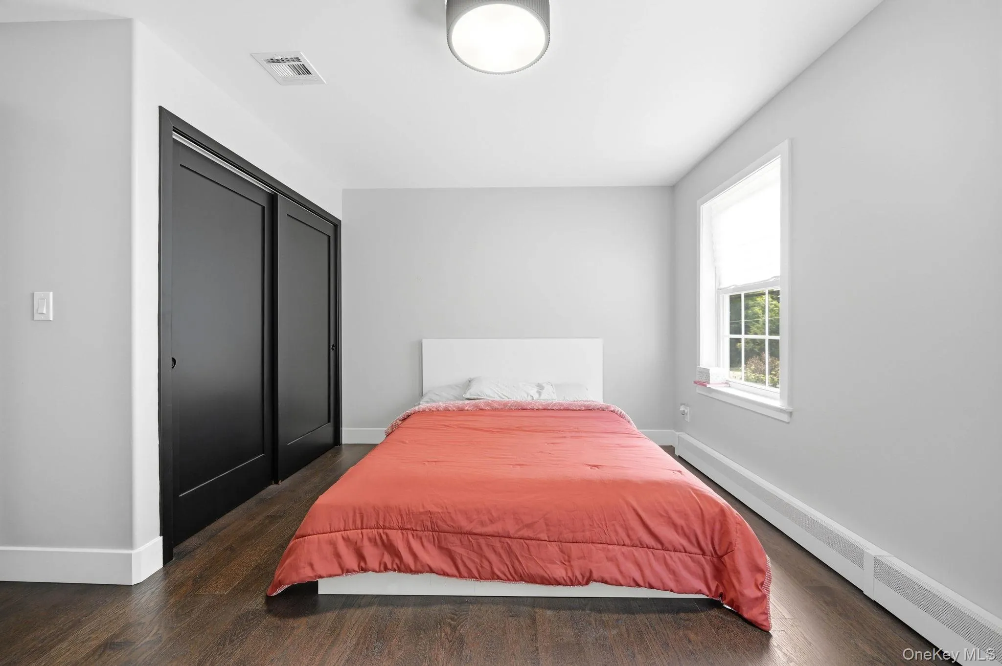 Bedroom featuring dark wood-finish flooring, light gray walls, and white trim Bedroom featuring dark wood-finish flooring, light gray walls, and white trim