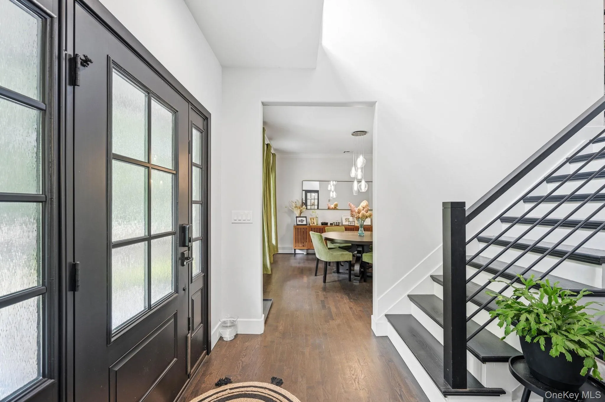 Entryway featuring dark wood-finish flooring and a black staircase with horizontal metal balusters Entryway featuring dark wood-finish flooring and a black staircase with horizontal metal balusters