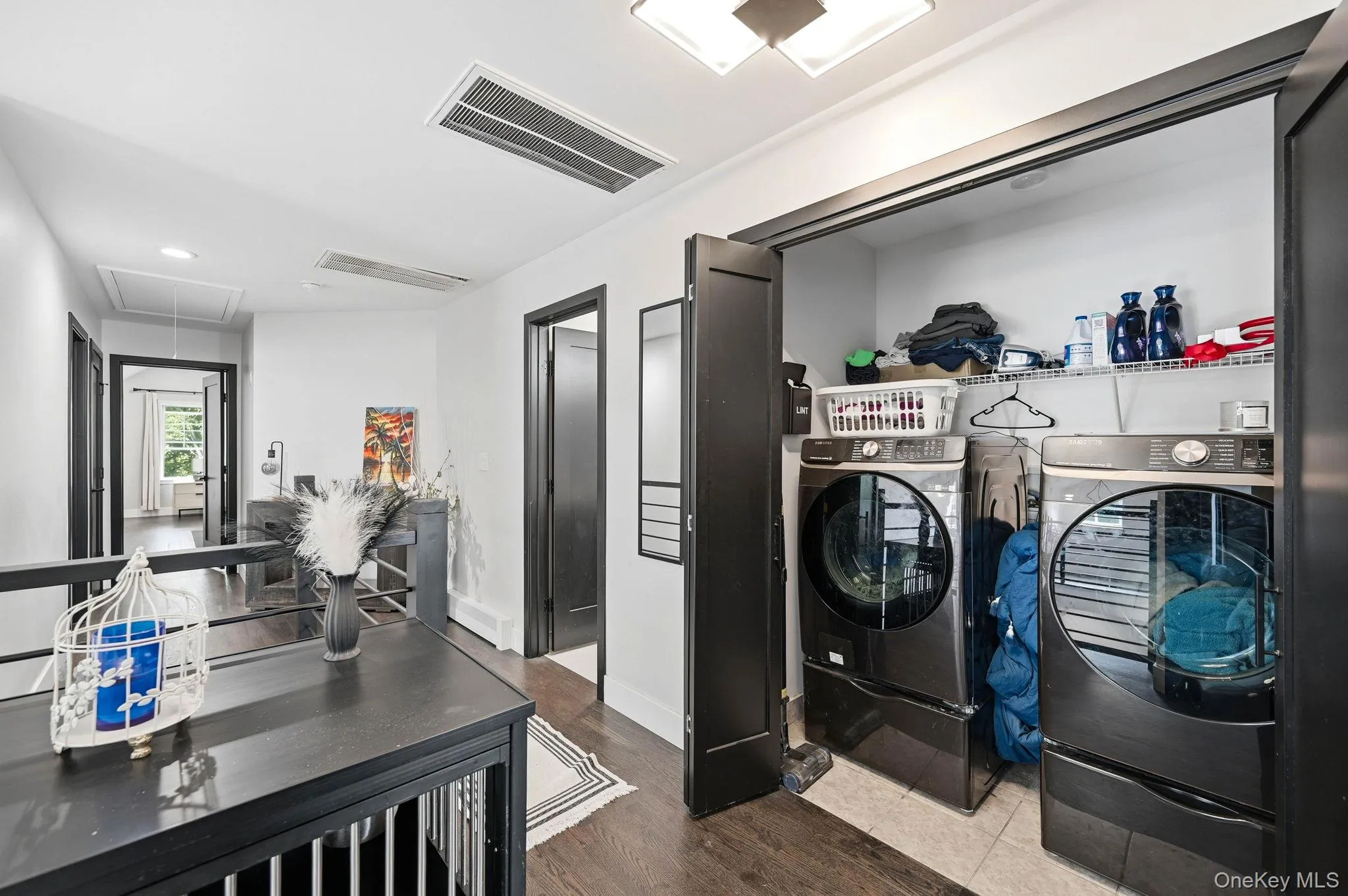 Convenient laundry closet with bi-fold doors, front-loading washer and dryer, and wire shelving located on second level Convenient laundry closet with bi-fold doors, front-loading washer and dryer, and wire shelving located on second level