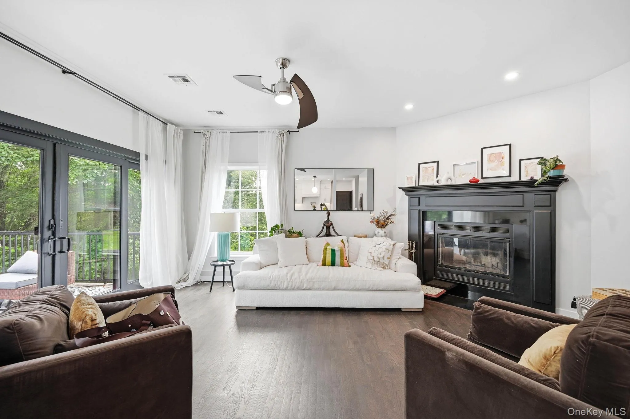 Living area with dark wood-finish flooring, featuring a black fireplace surround and mantel Living area with dark wood-finish flooring, featuring a black fireplace surround and mantel