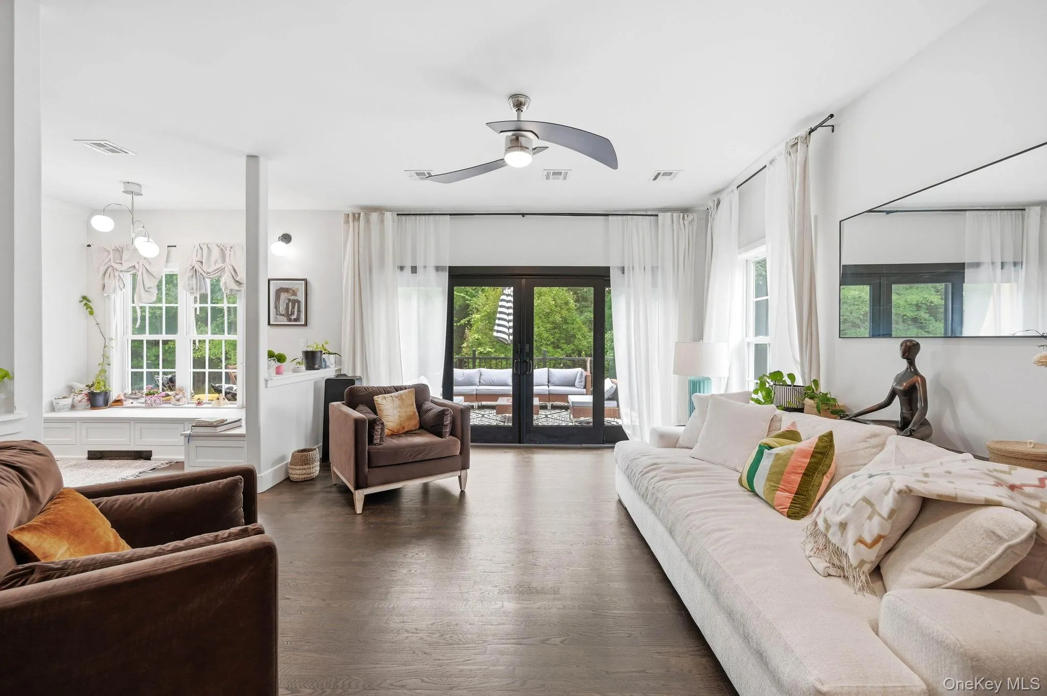 Living area featuring dark wood-finish flooring, a modern ceiling fan, and white walls Living area featuring dark wood-finish flooring, a modern ceiling fan, and white walls
