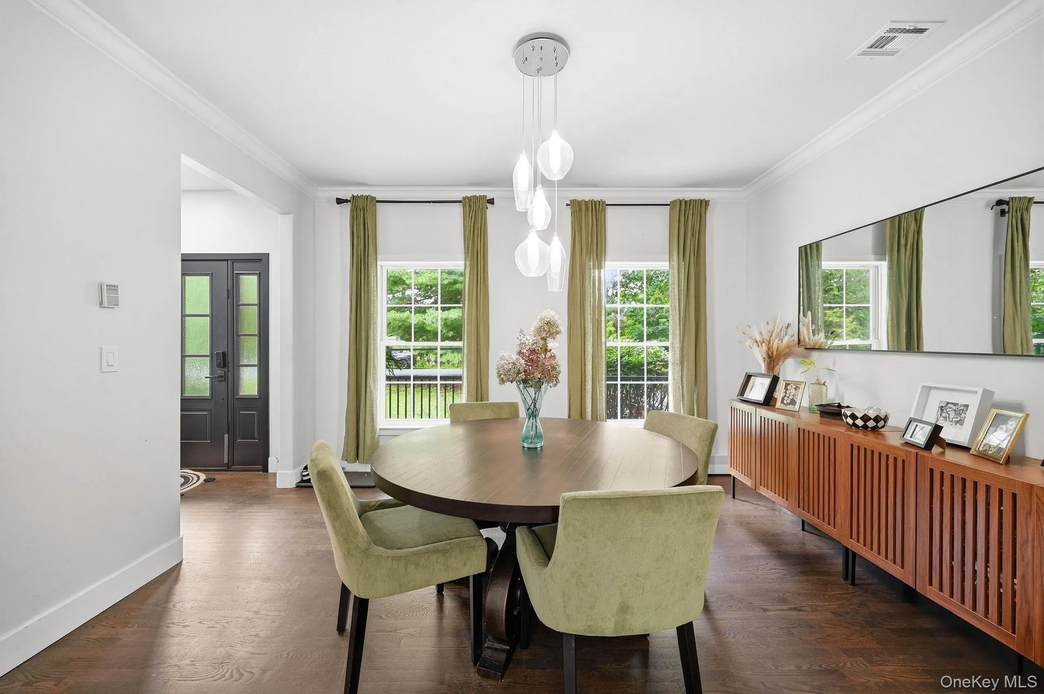 Dining area featuring wood-finish flooring, a contemporary chandelier, crown molding, and multiple windows providing lots of natural light Dining area featuring wood-finish flooring, a contemporary chandelier, crown molding, and multiple windows providing lots of natural light
