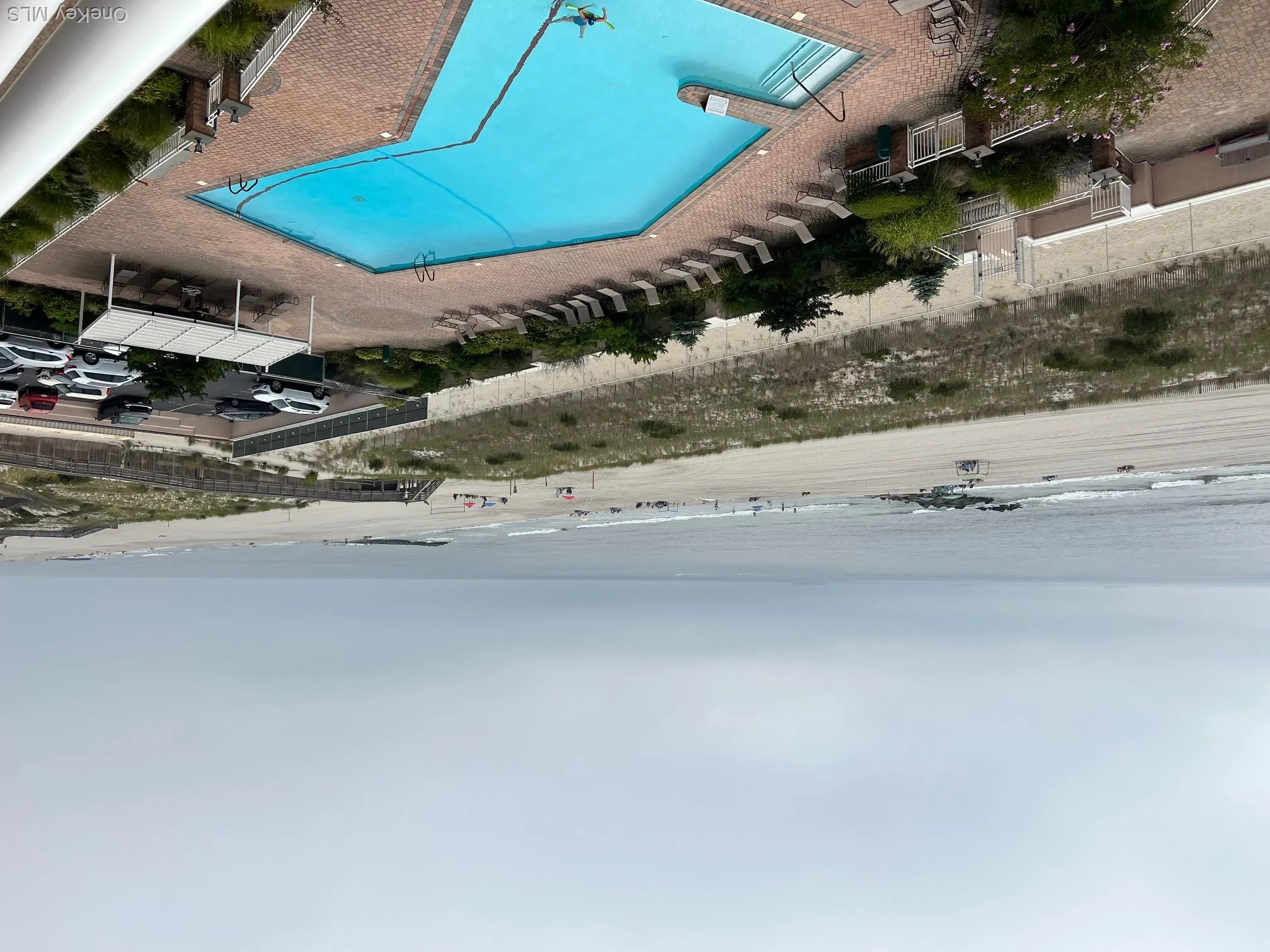 Community pool featuring a patio area and view of water and beach Community pool featuring a patio area and view of water and beach