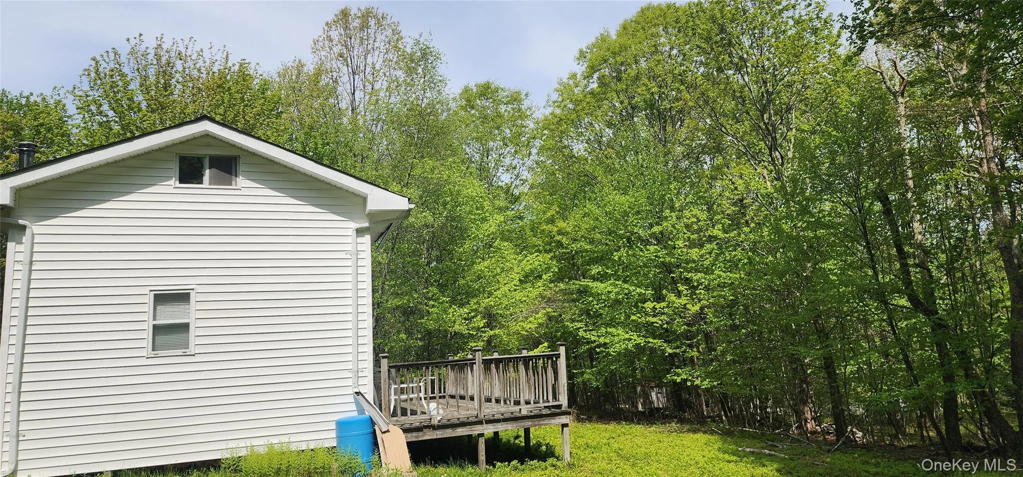 View of home's exterior featuring a wooden deck and a lawn View of home's exterior featuring a wooden deck and a lawn