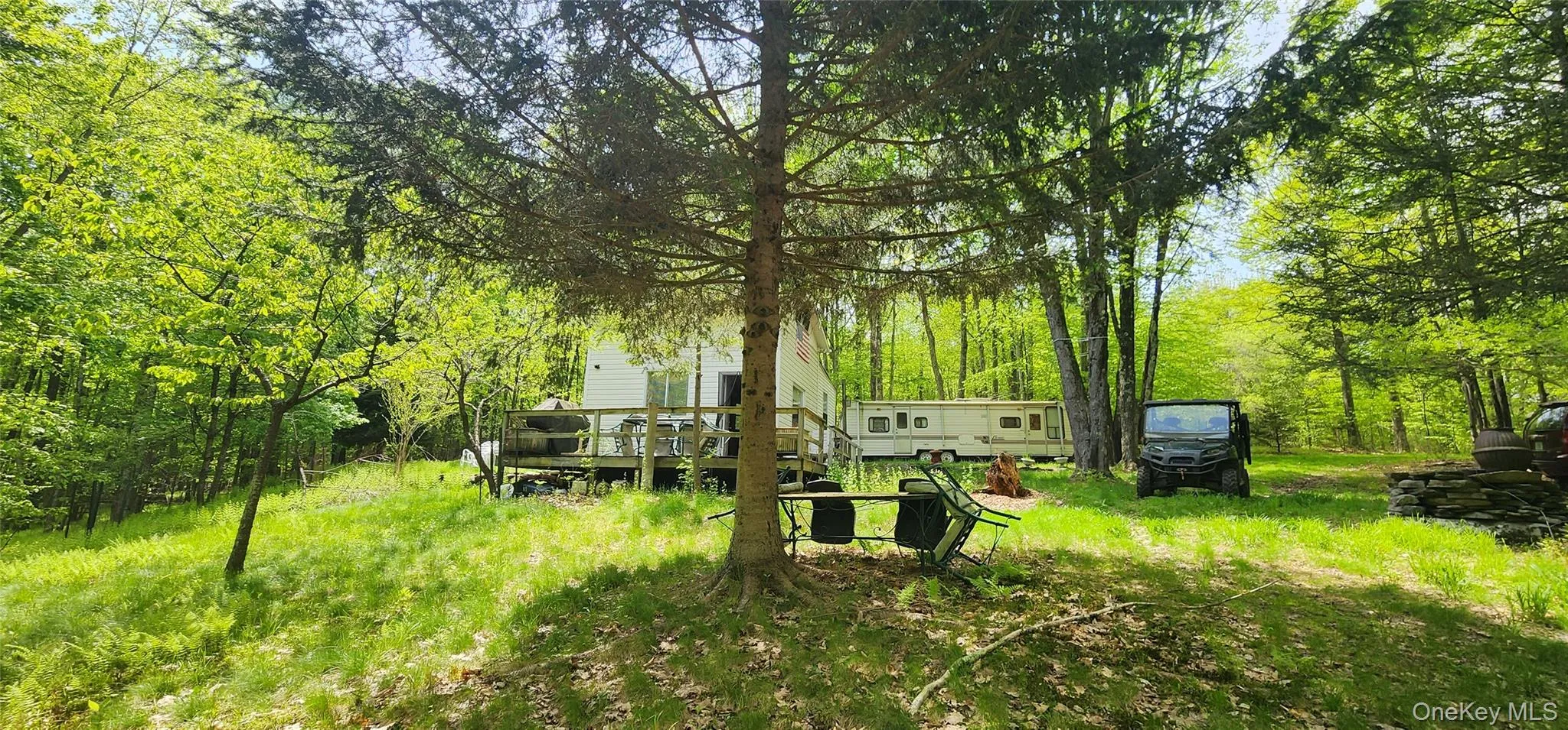 View of yard featuring a wooden deck and a forest view View of yard featuring a wooden deck and a forest view
