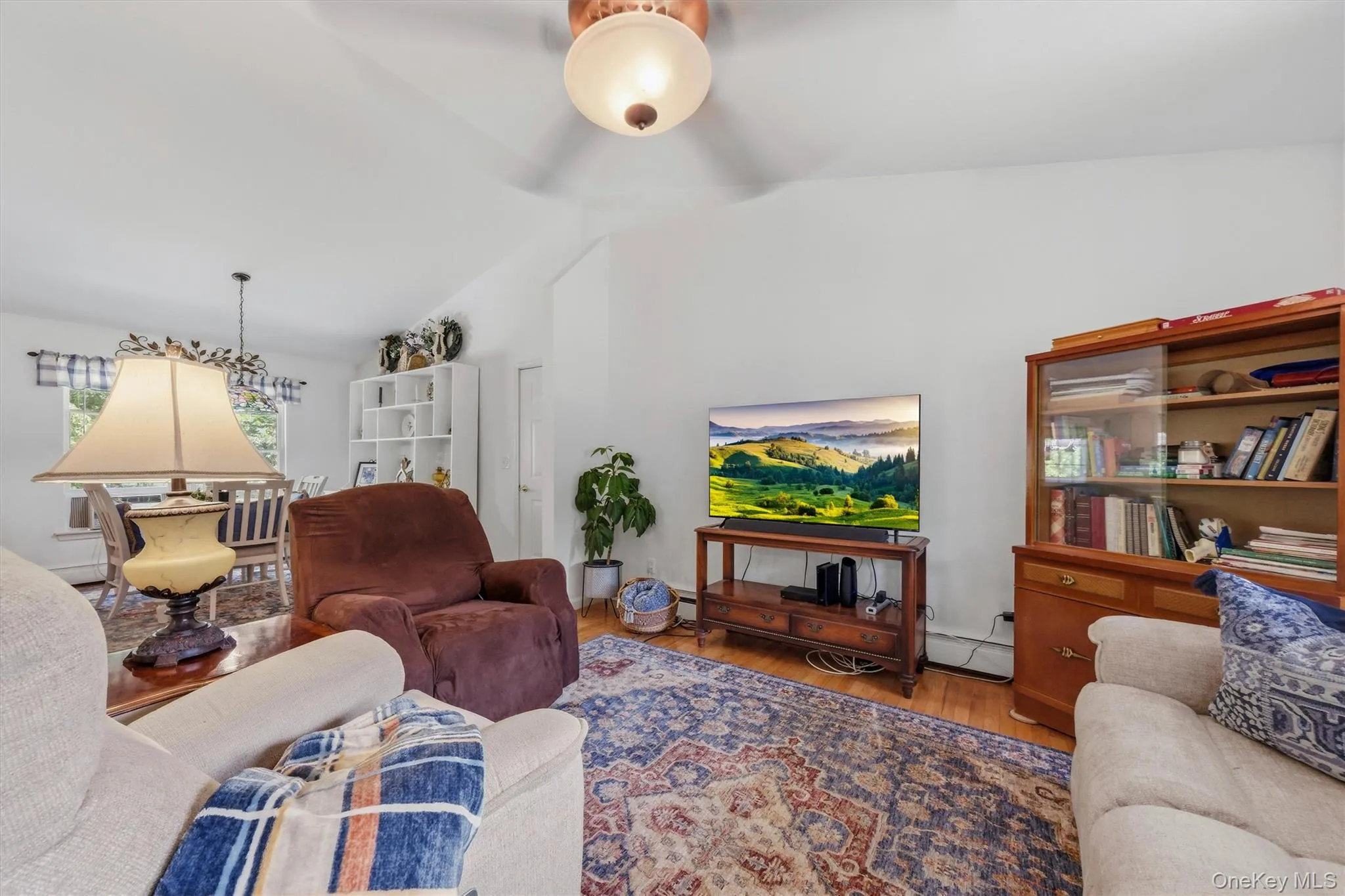 Vaulted ceiling with a ceiling fan, wood-finish flooring, and a built-in bookcase Vaulted ceiling with a ceiling fan, wood-finish flooring, and a built-in bookcase