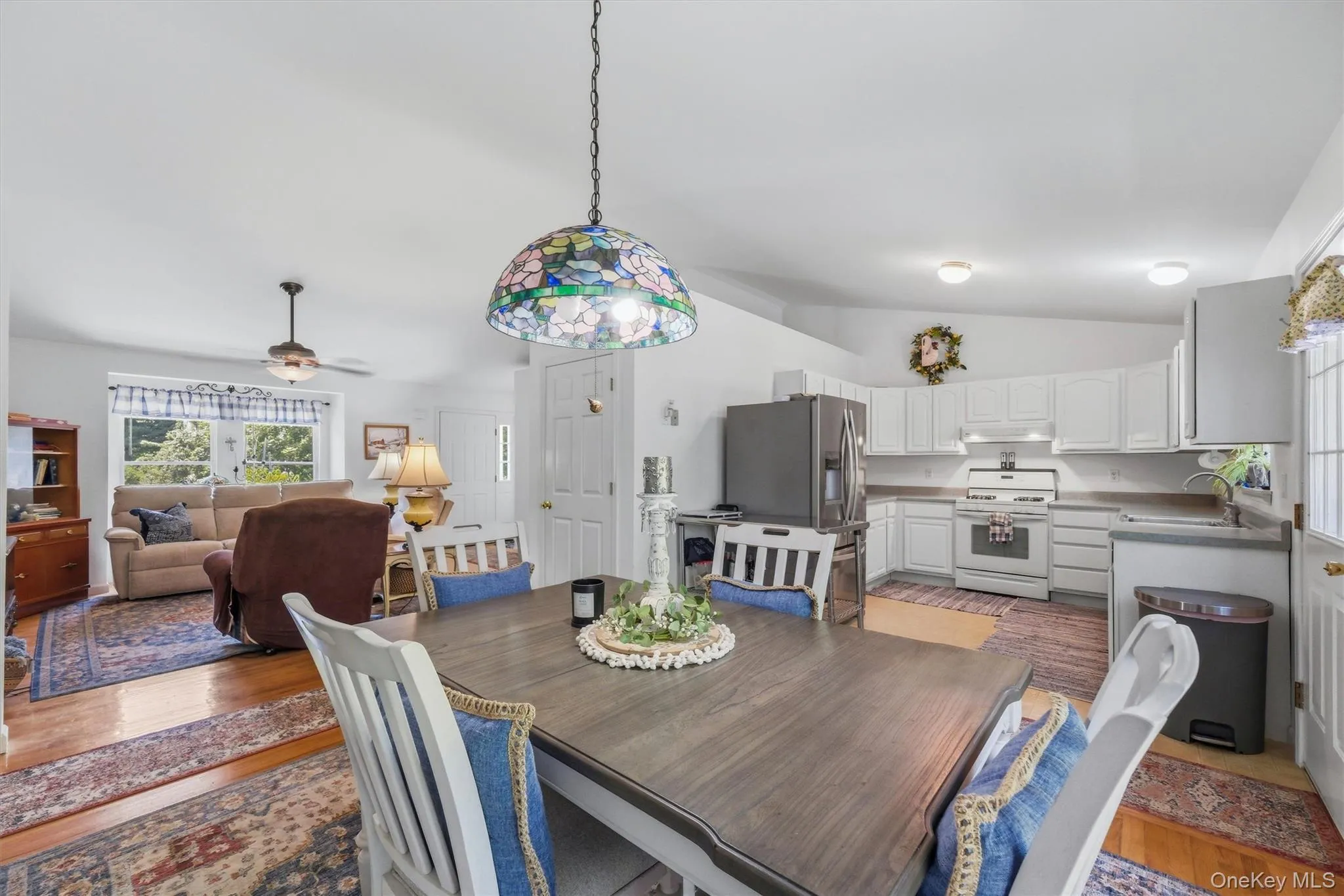 Open-concept interior featuring wood-finish flooring, white cabinetry, and stainless steel appliances Open-concept interior featuring wood-finish flooring, white cabinetry, and stainless steel appliances