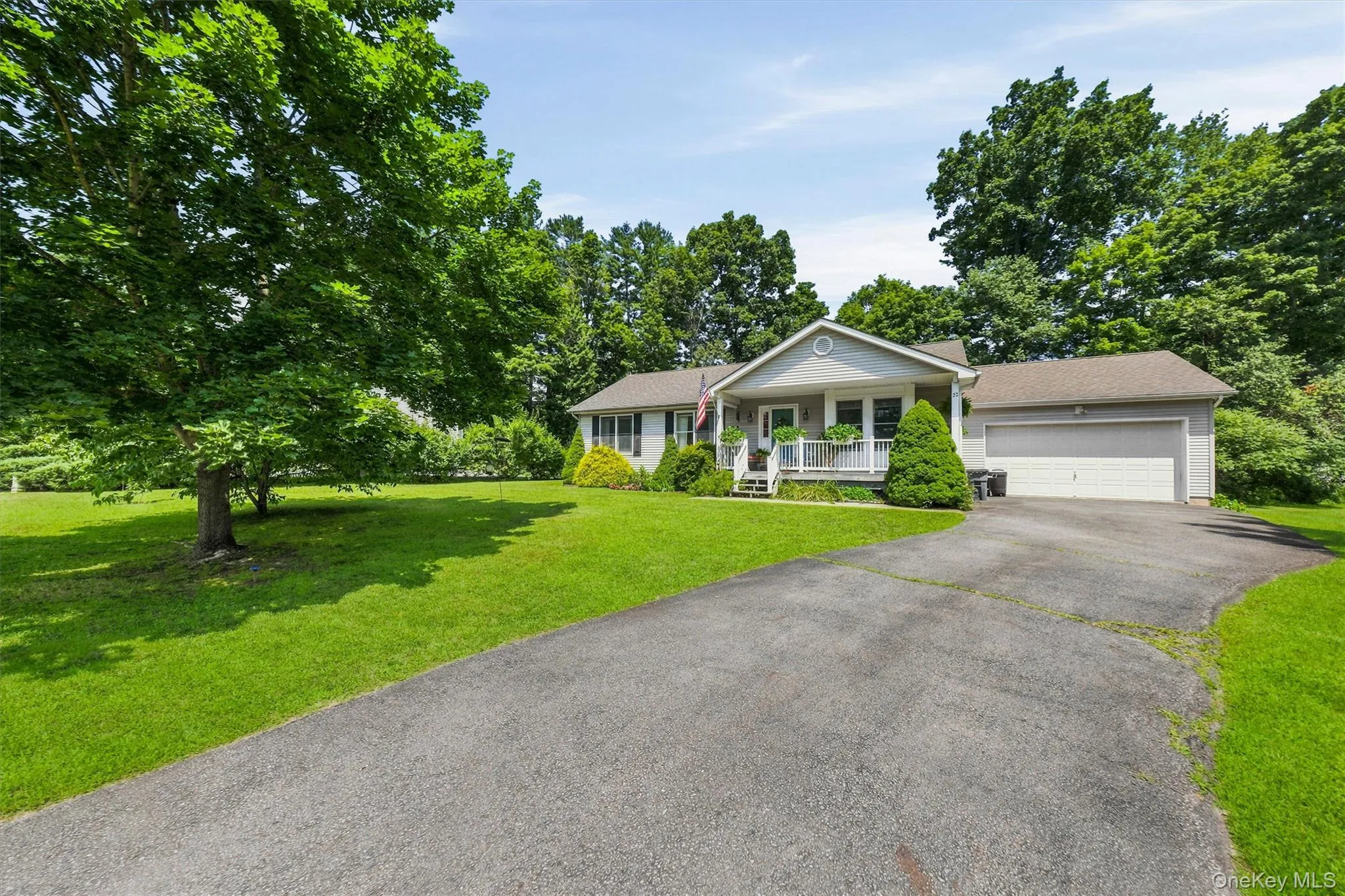 Ranch-style residence featuring a covered front porch, attached two-car garage, and a paved driveway Ranch-style residence featuring a covered front porch, attached two-car garage, and a paved driveway