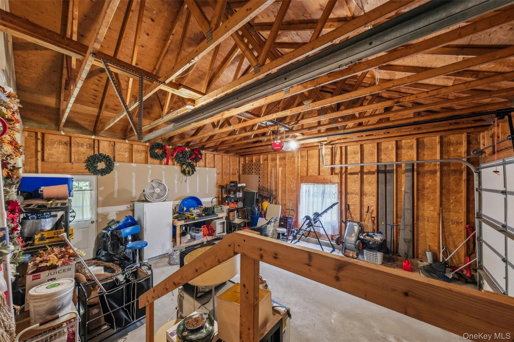 Concrete flooring with exposed wood beam ceiling, featuring a garage door, and built-in shelving Concrete flooring with exposed wood beam ceiling, featuring a garage door, and built-in shelving