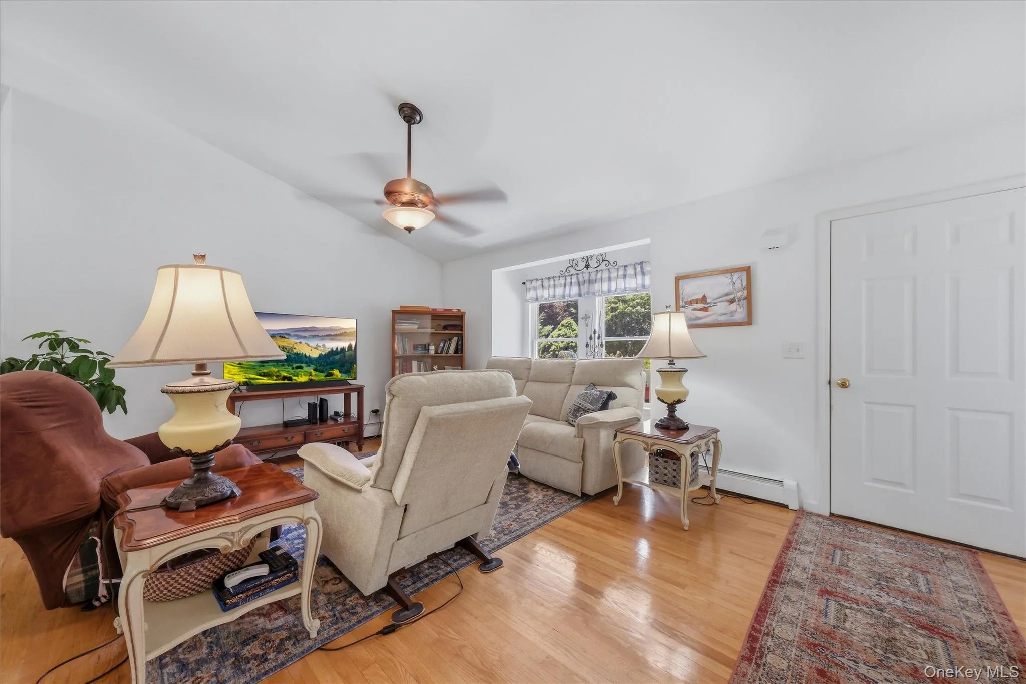 Vaulted ceiling with a ceiling fan, light wood-finish flooring, white walls, and a multi-pane window Vaulted ceiling with a ceiling fan, light wood-finish flooring, white walls, and a multi-pane window