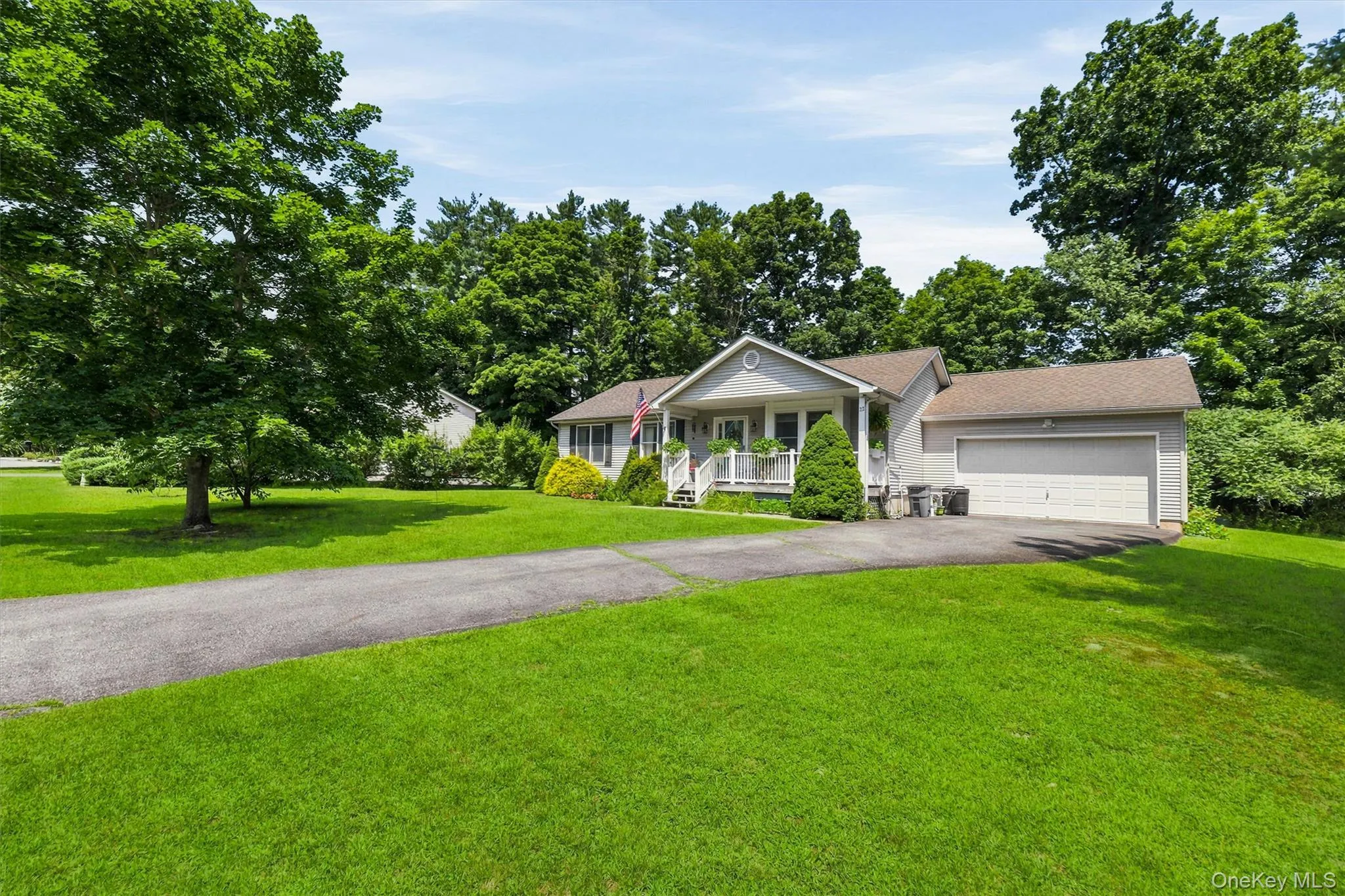 Single-story residence with a covered front porch, attached garage, and asphalt driveway Single-story residence with a covered front porch, attached garage, and asphalt driveway