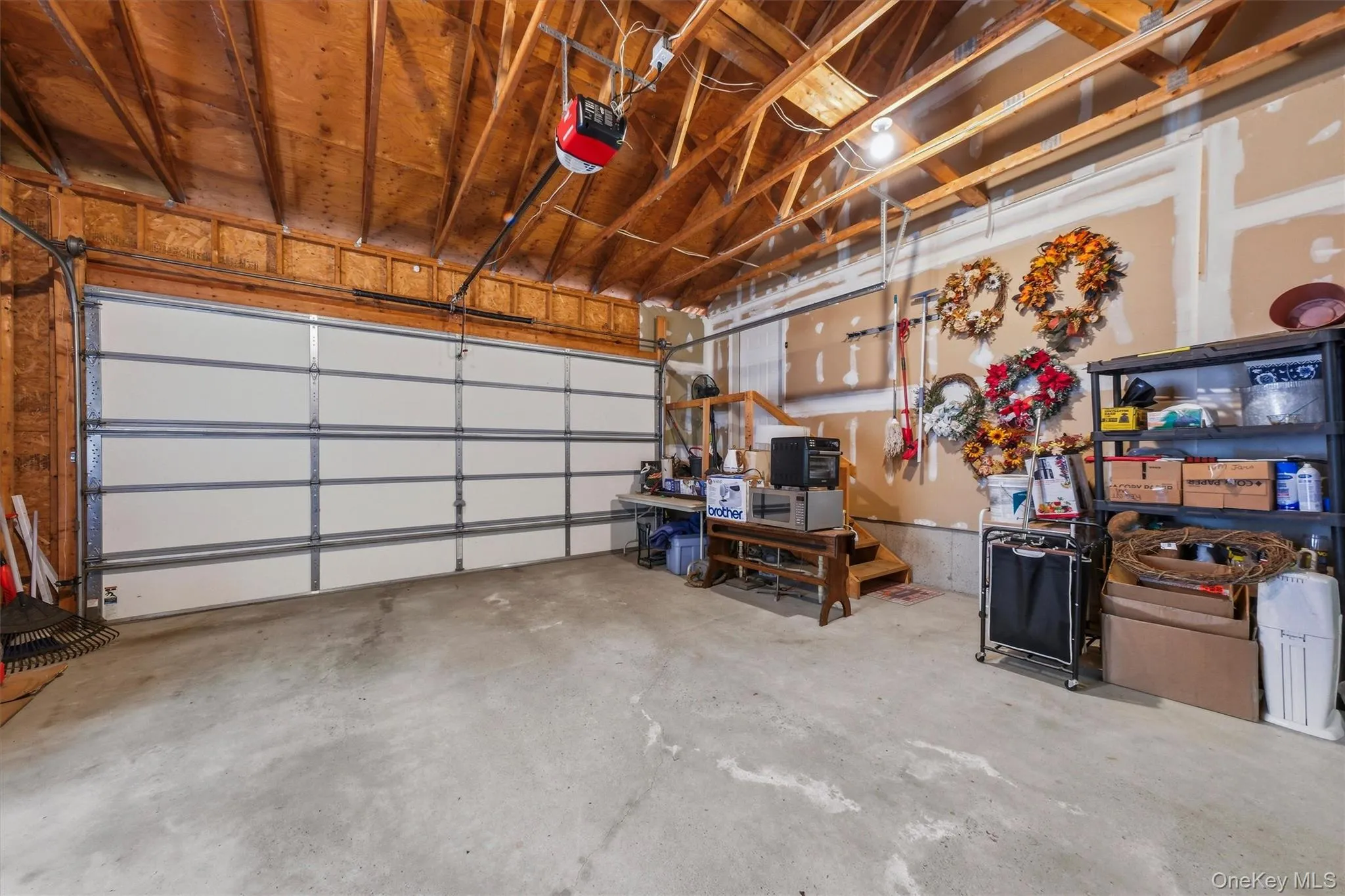 Concrete flooring with exposed wood beam ceiling, featuring a garage door, and built-in shelving Concrete flooring with exposed wood beam ceiling, featuring a garage door, and built-in shelving