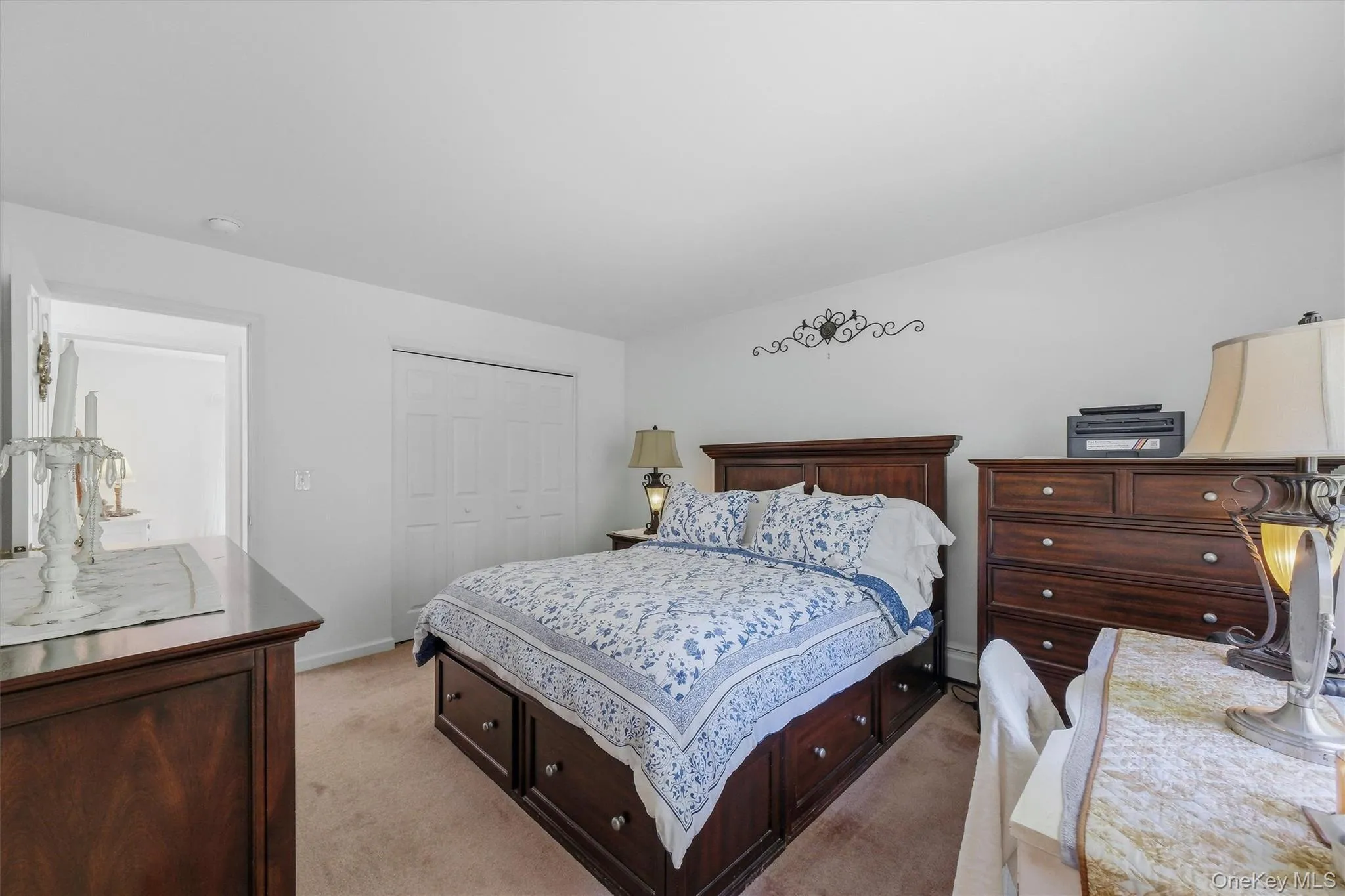 Neutral wall colors, carpet flooring, a built-in closet with bi-fold doors, and a doorway leading to another area Neutral wall colors, carpet flooring, a built-in closet with bi-fold doors, and a doorway leading to another area