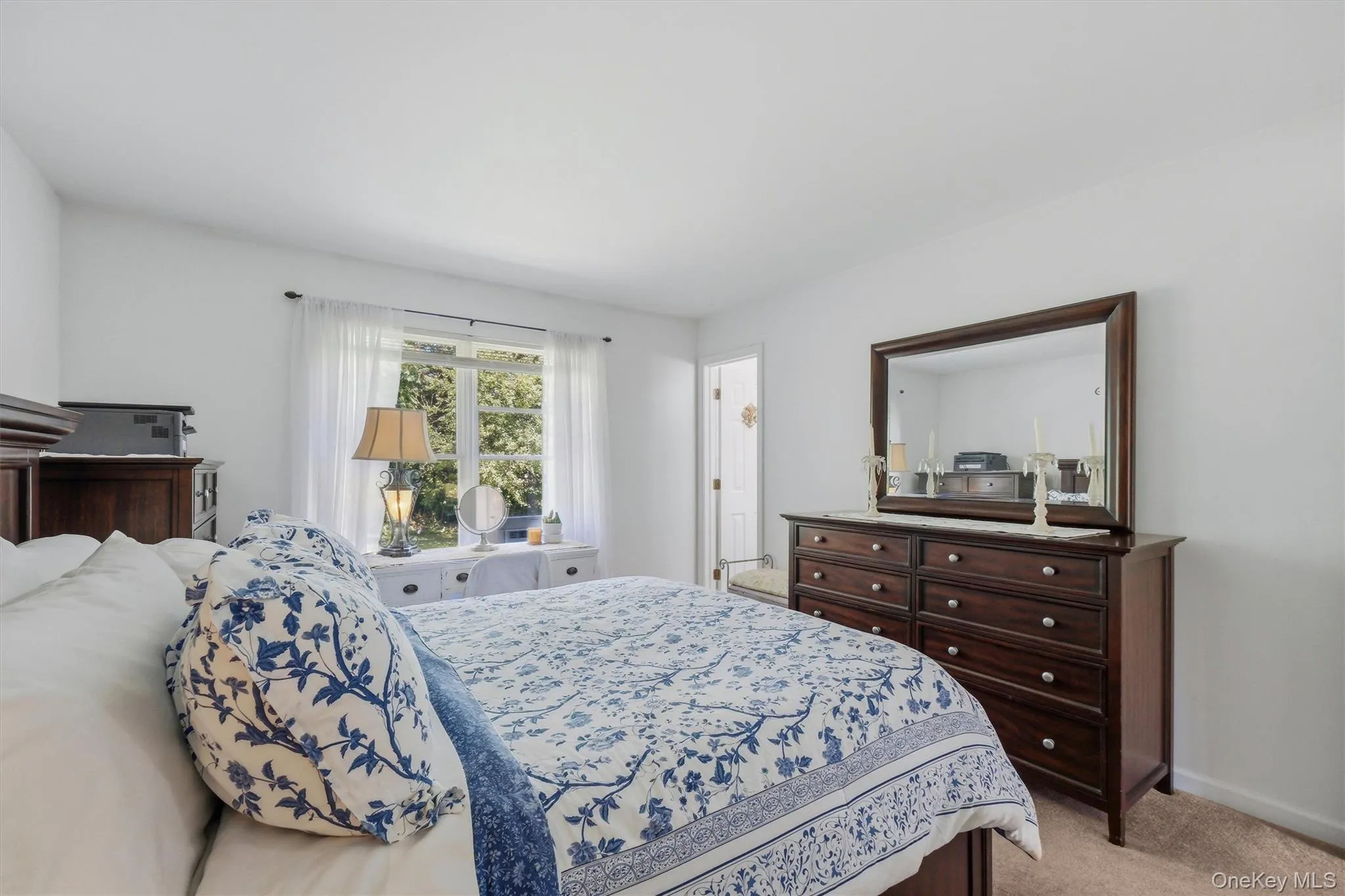 Bright room with a large window, neutral wall color, and carpeted flooring Bright room with a large window, neutral wall color, and carpeted flooring