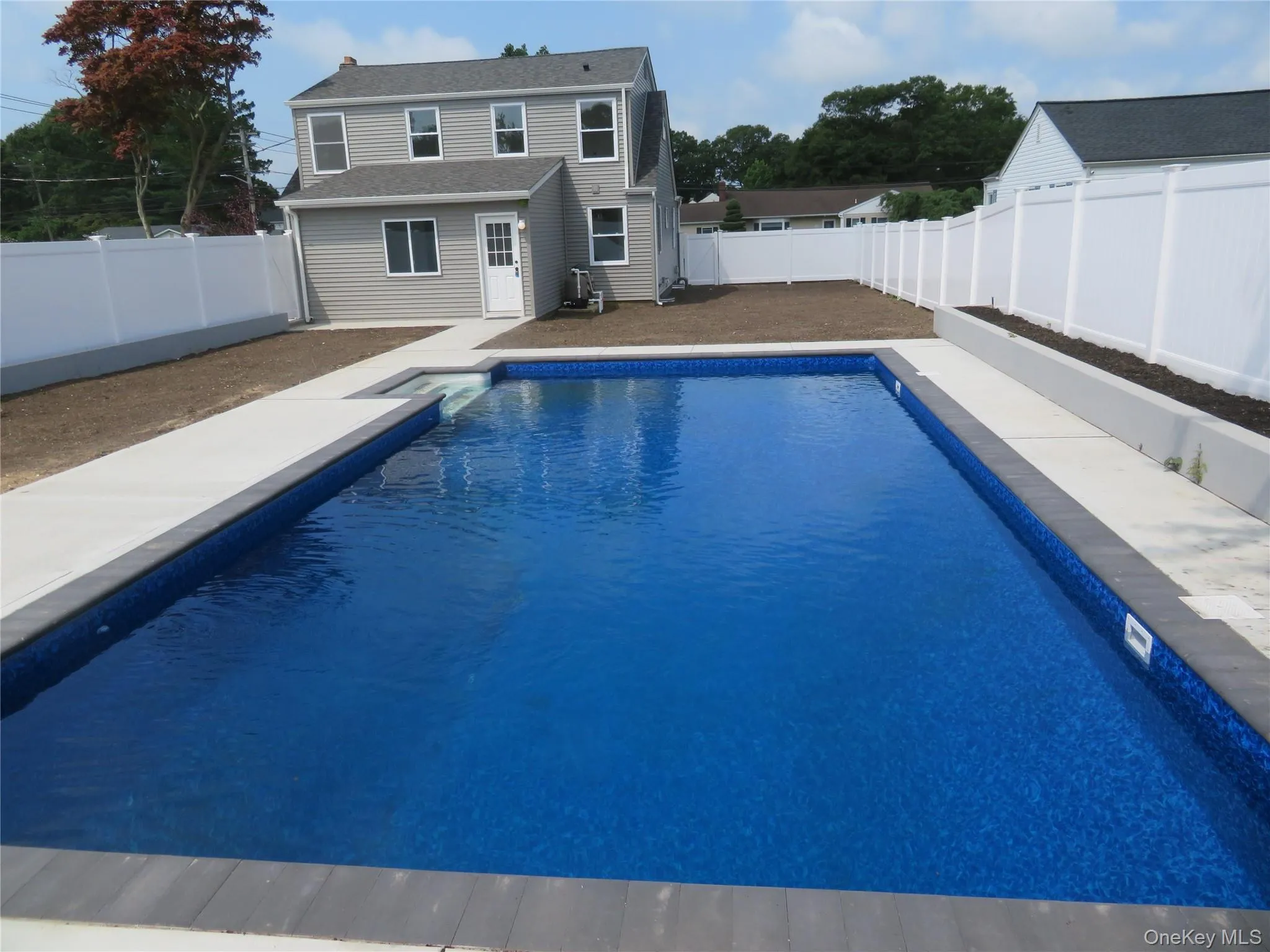 Rectangular in-ground pool featuring a bright blue interior, a concrete surround, and integrated steps Rectangular in-ground pool featuring a bright blue interior, a concrete surround, and integrated steps