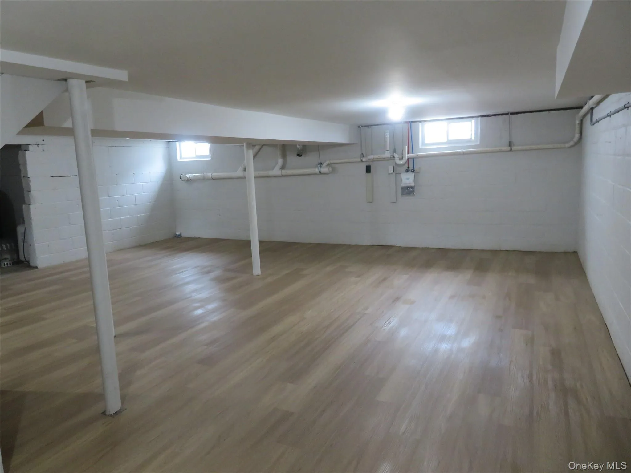 Spacious lower level featuring waterproof wood-finish flooring, white painted block walls, and overhead lighting Spacious lower level featuring waterproof wood-finish flooring, white painted block walls, and overhead lighting