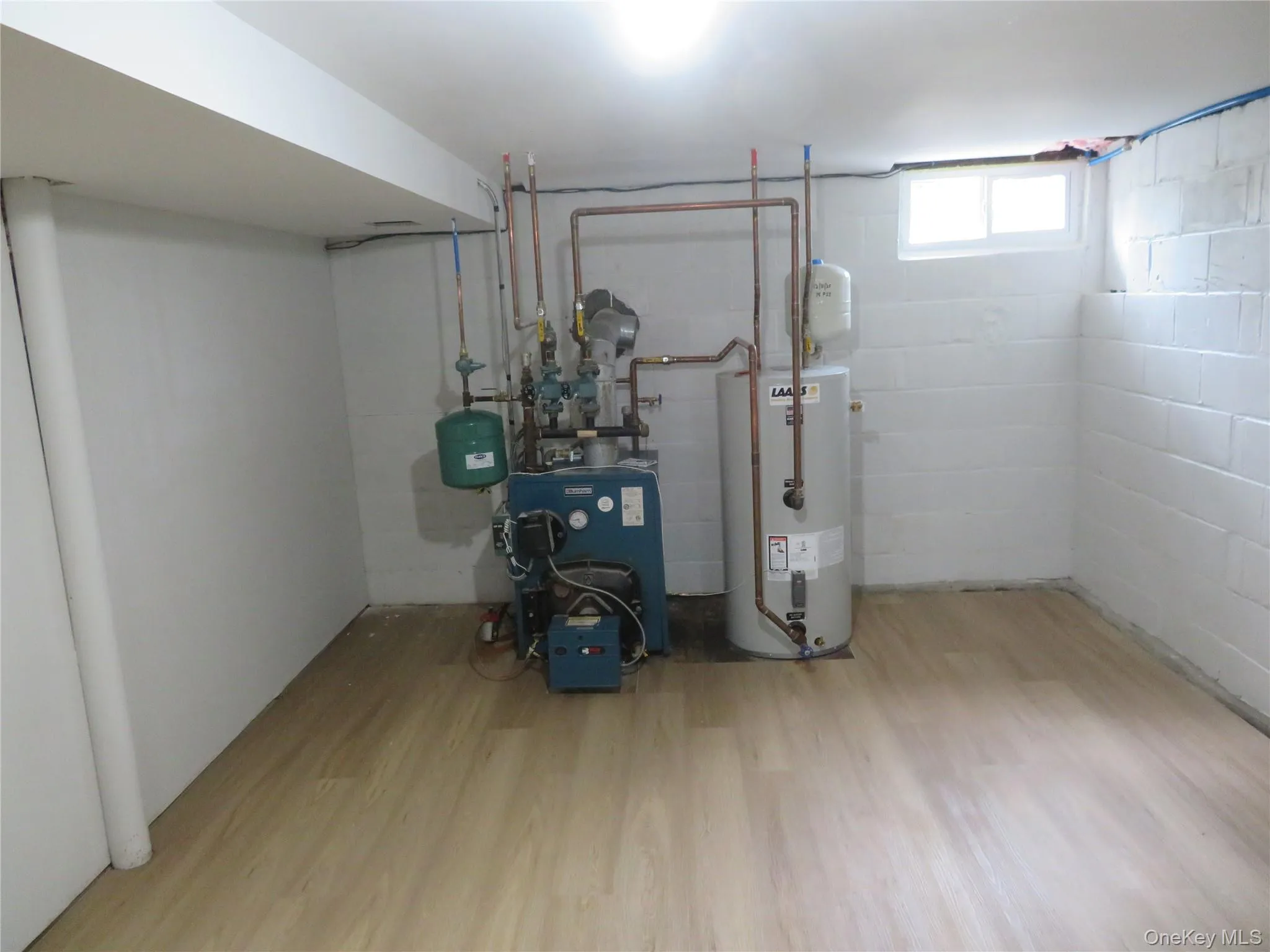 Utility space featuring a boiler system, water heater, and light wood-finish flooring Utility space featuring a boiler system, water heater, and light wood-finish flooring