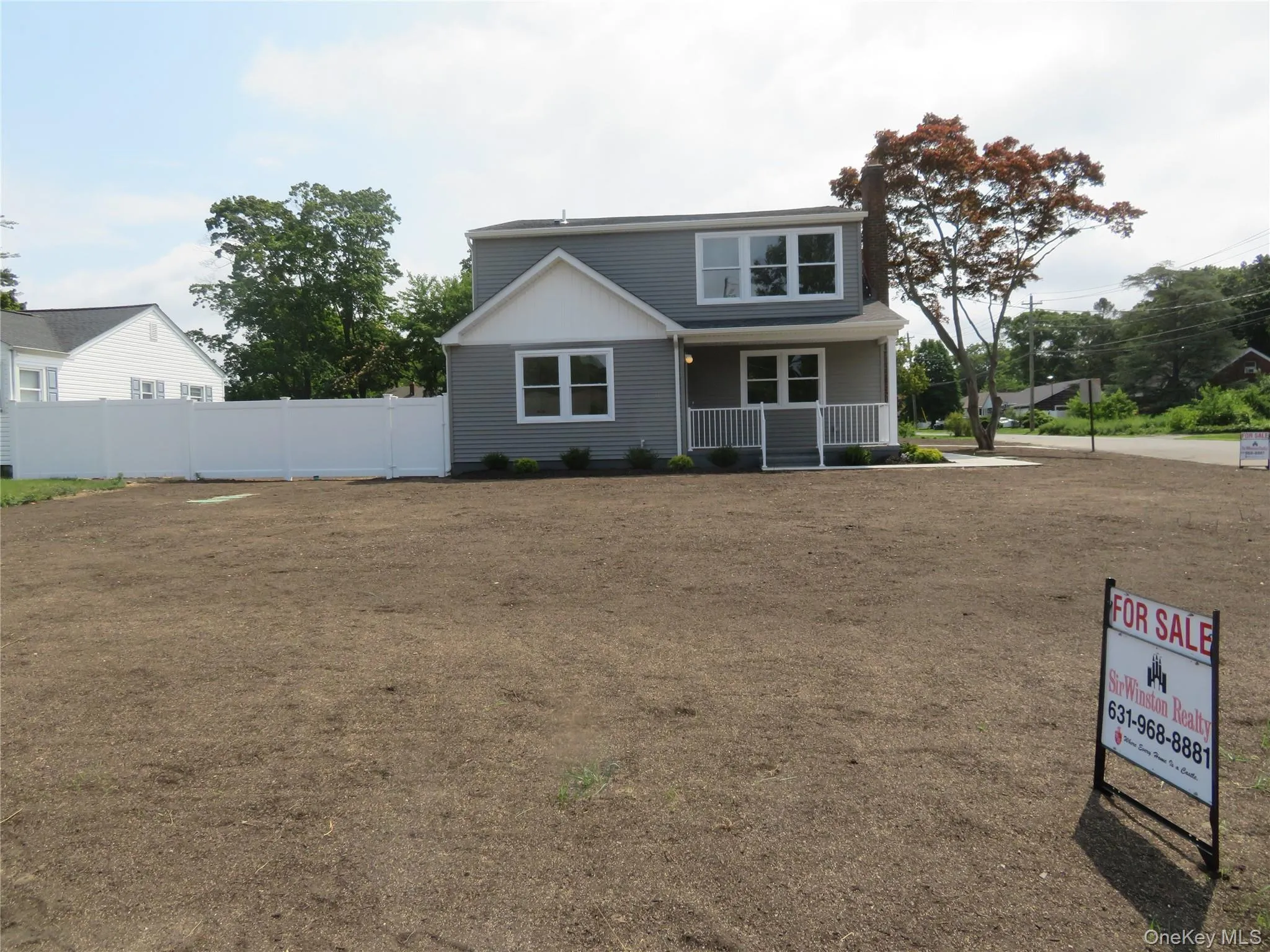 Two-story home with light gray siding, white trim, and a covered front porch featuring white railings Two-story home with light gray siding, white trim, and a covered front porch featuring white railings
