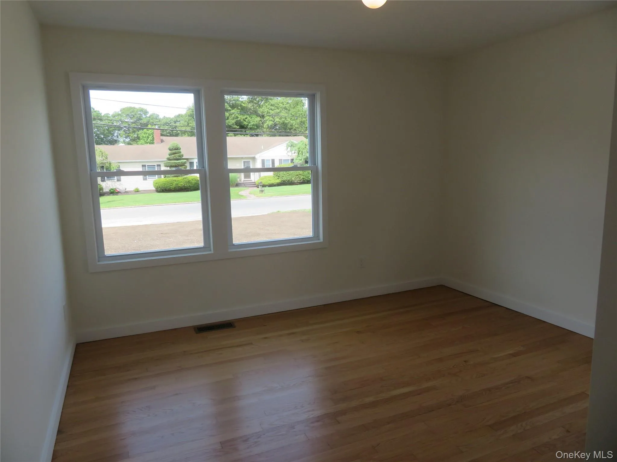 Bright interior space featuring wood-finish flooring, white baseboards, and neutral wall tones Bright interior space featuring wood-finish flooring, white baseboards, and neutral wall tones