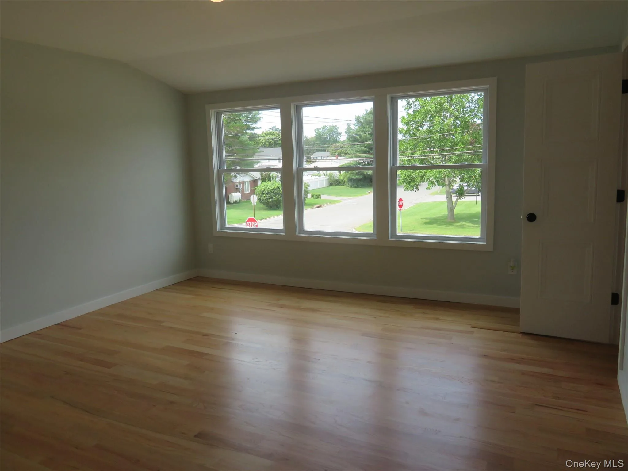 Master bedroom. Bright interior space featuring three large windows, light wood-finish flooring, and white trim Master bedroom. Bright interior space featuring three large windows, light wood-finish flooring, and white trim