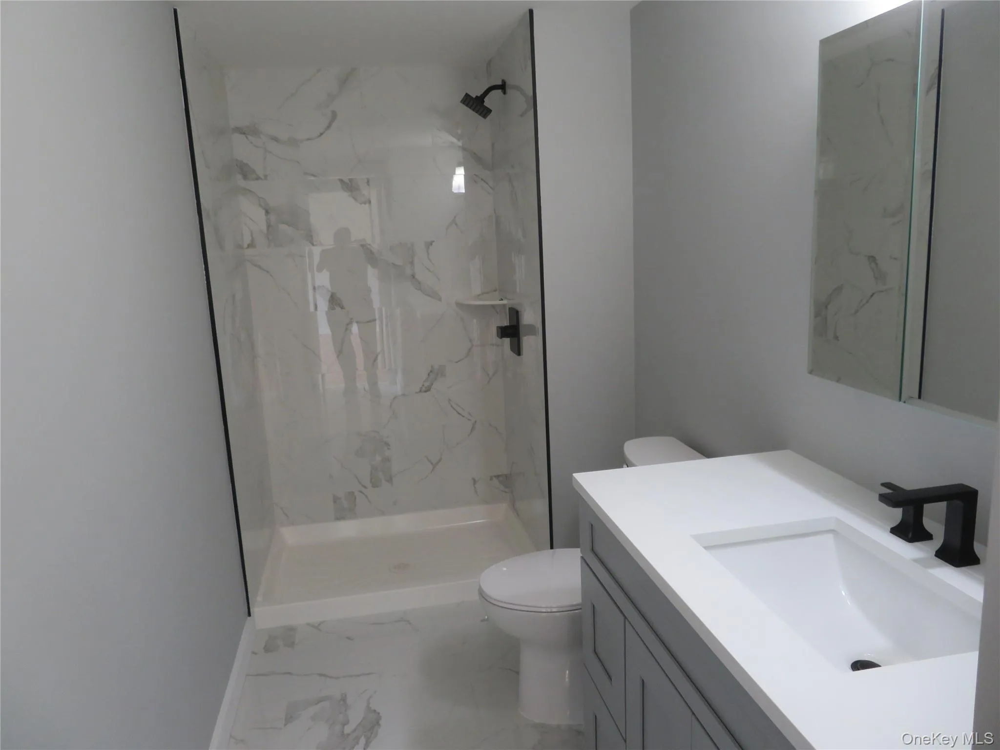 Master Bath. A Contemporary bathroom featuring a walk-in shower with stone-finish paneling, a sleek white shower pan, and matte black fixtures Master Bath. A Contemporary bathroom featuring a walk-in shower with stone-finish paneling, a sleek white shower pan, and matte black fixtures
