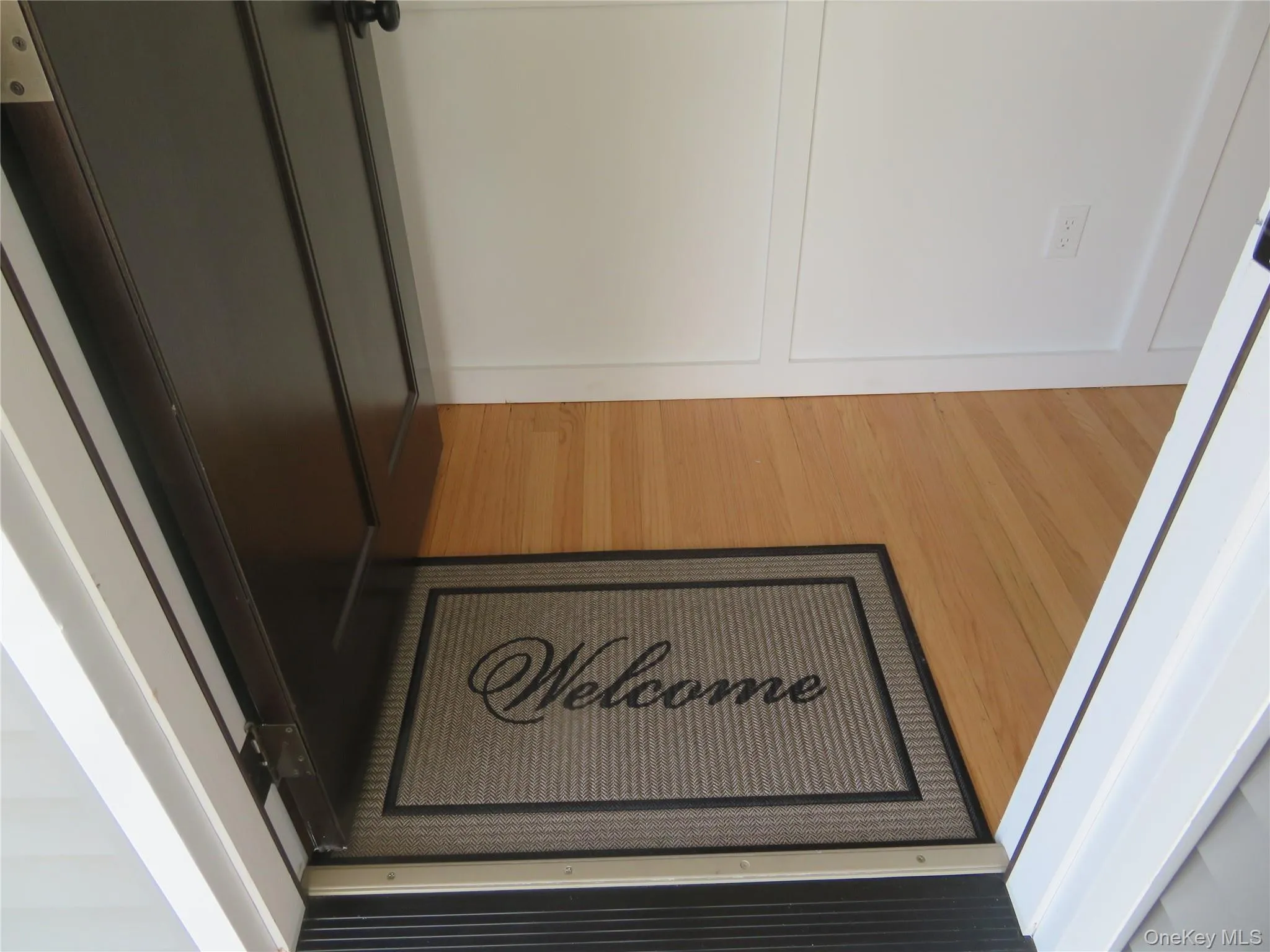 Front door Light wood-finish flooring complements white wainscoting and baseboards Front door Light wood-finish flooring complements white wainscoting and baseboards