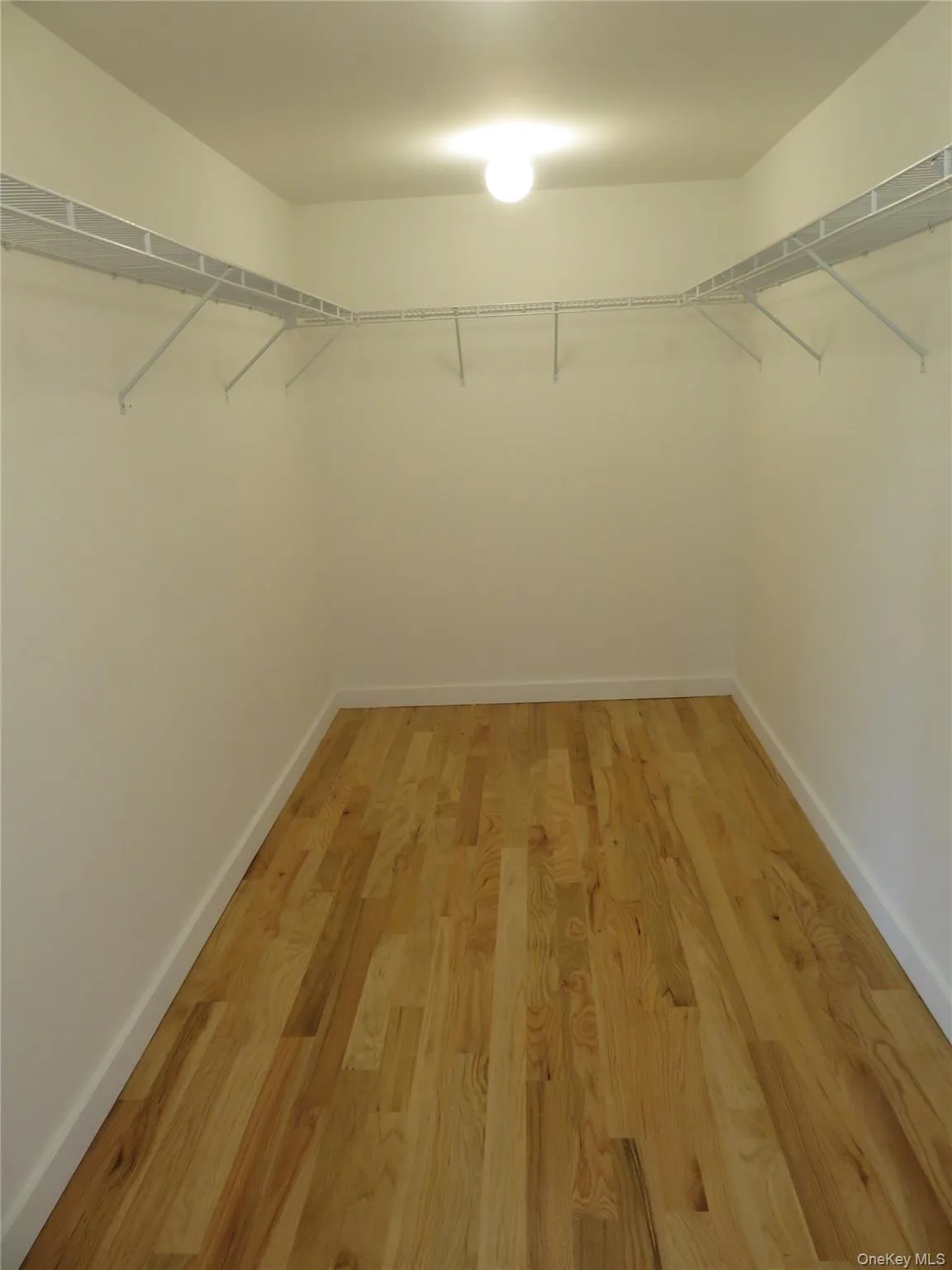 Master Bedroom. Walk-in closet featuring light wood-finish flooring, white walls, white baseboards, a flush-mount ceiling light, and white wire shelving Master Bedroom. Walk-in closet featuring light wood-finish flooring, white walls, white baseboards, a flush-mount ceiling light, and white wire shelving