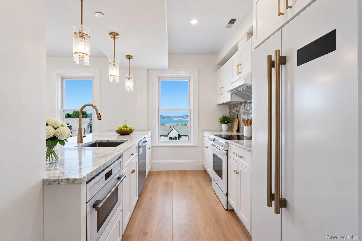Modern Renovated Kitchen — Bright and elegant with white cabinetry, stainless-steel appliances, beautiful countertops and pendant lighting, complemented by natural light and scenic Hudson River views. Modern Renovated Kitchen — Bright and elegant with white cabinetry, stainless-steel appliances, beautiful countertops and pendant lighting, complemented by natural light and scenic Hudson River views.
