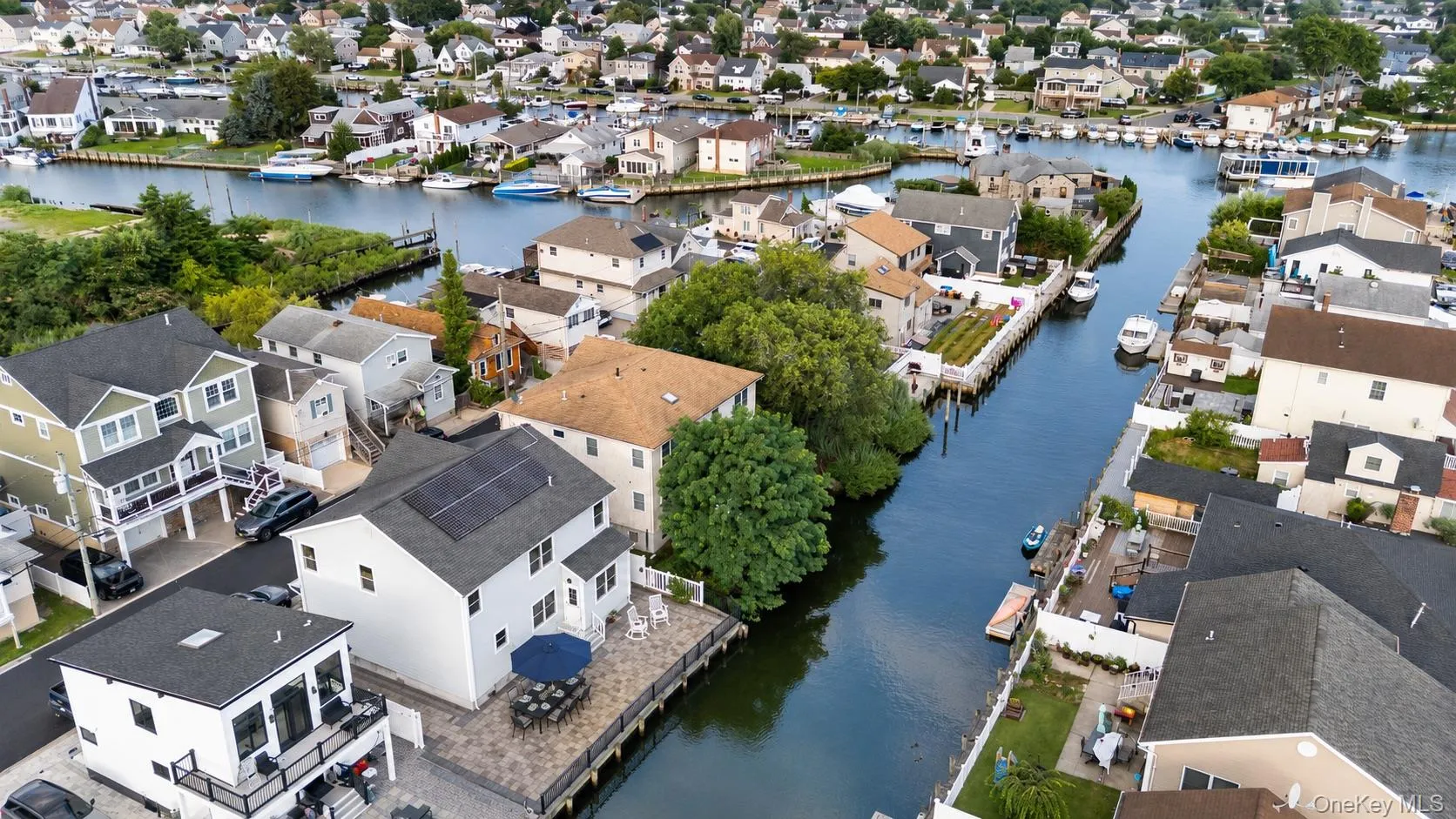 Waterfront property featuring a paver patio, a wooden dock, and solar panels on the roof Waterfront property featuring a paver patio, a wooden dock, and solar panels on the roof
