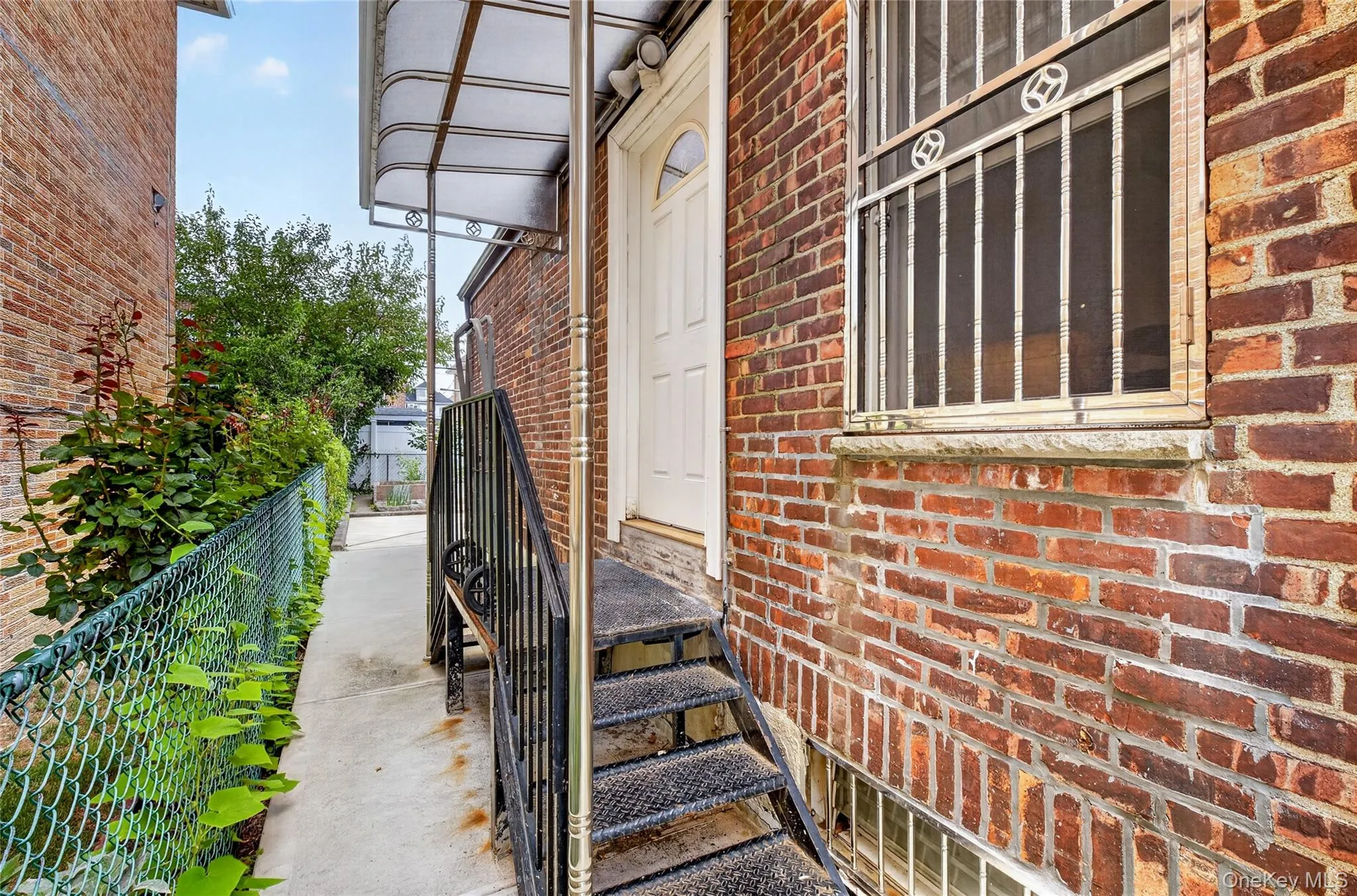 Brick exterior with a side walkway, featuring metal stairs leading to an entry door Brick exterior with a side walkway, featuring metal stairs leading to an entry door