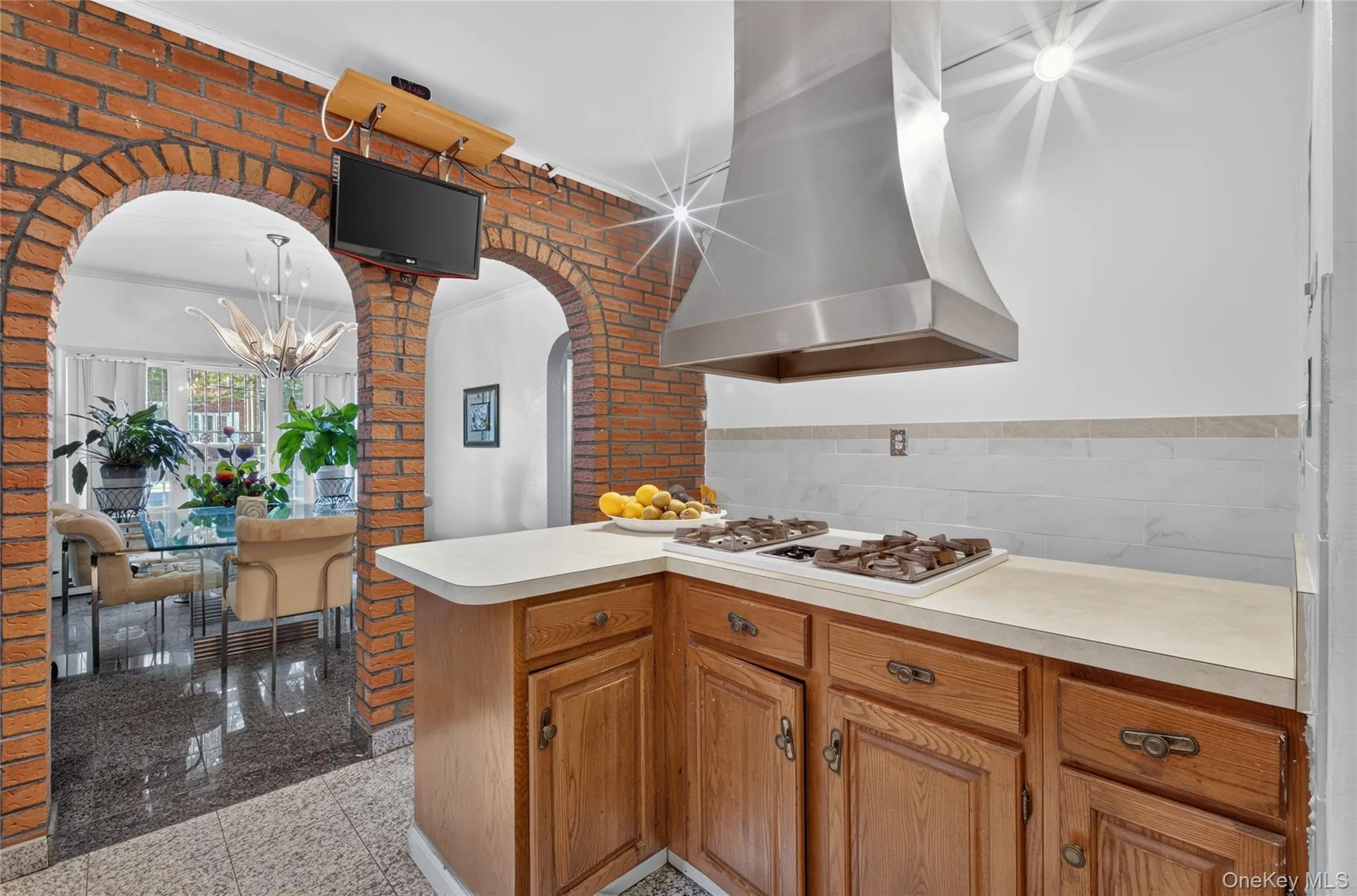 Kitchen featuring a stainless steel range hood, built-in gas cooktop, and wood cabinetry Kitchen featuring a stainless steel range hood, built-in gas cooktop, and wood cabinetry