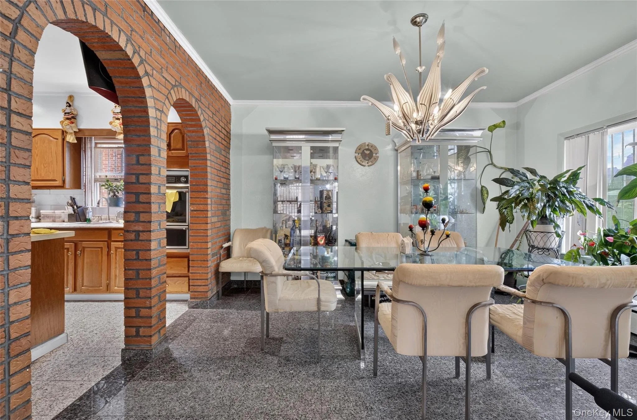Dining space featuring brick archways, granite-finish flooring, and a contemporary chandelier Dining space featuring brick archways, granite-finish flooring, and a contemporary chandelier